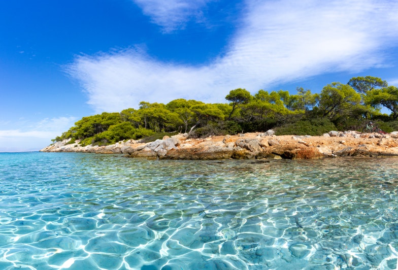 view of the Aponissos beach, Greece, where turquoise waters meet with the green forest and the clear blue sky