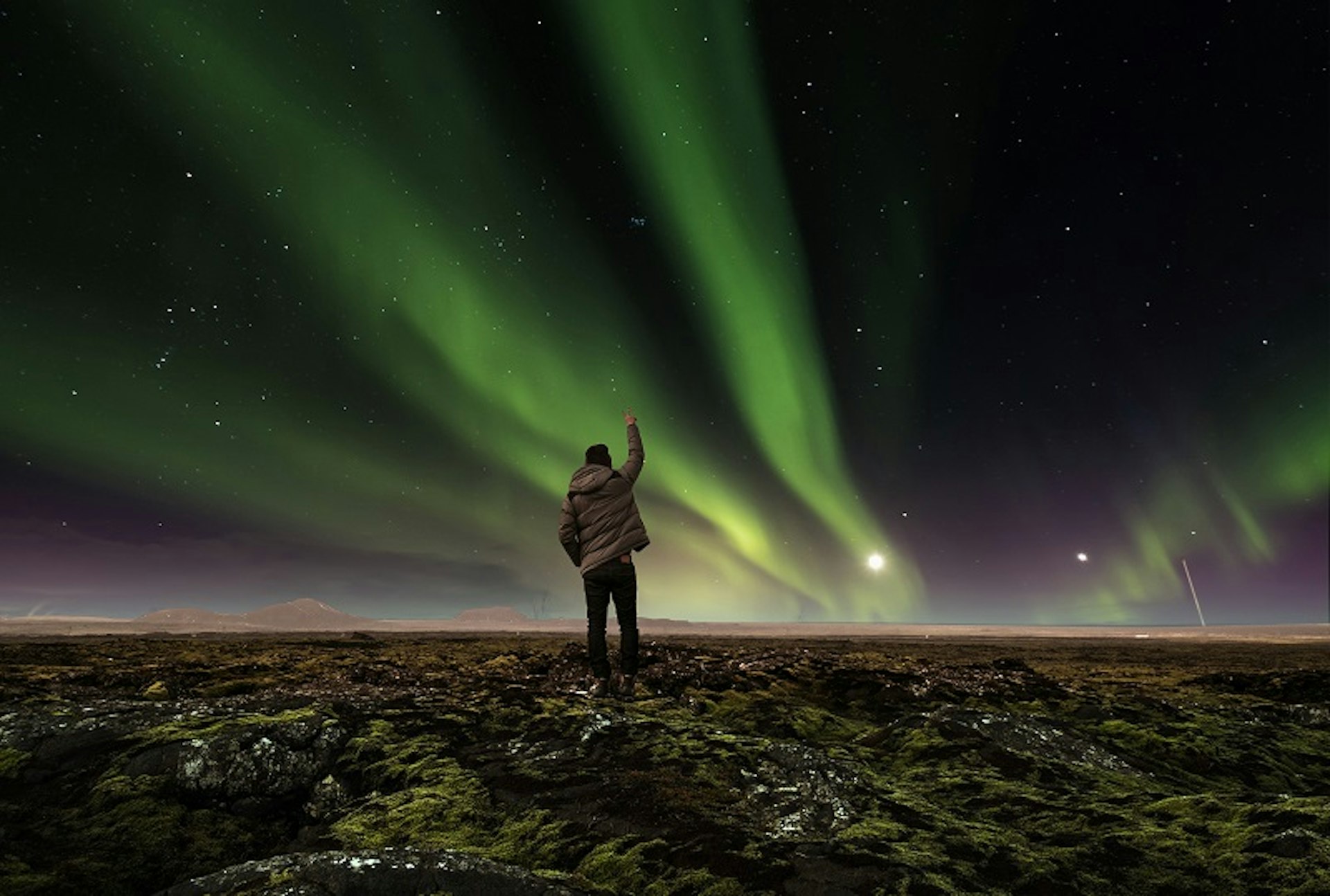 A person standing under the northern lights in Iceland