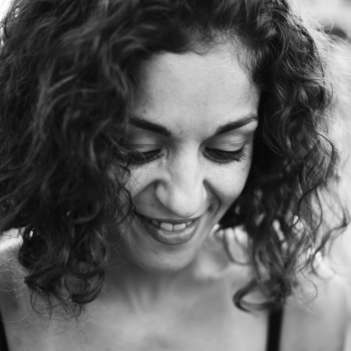 Image description: Black and white image of a woman looking down and smiling.