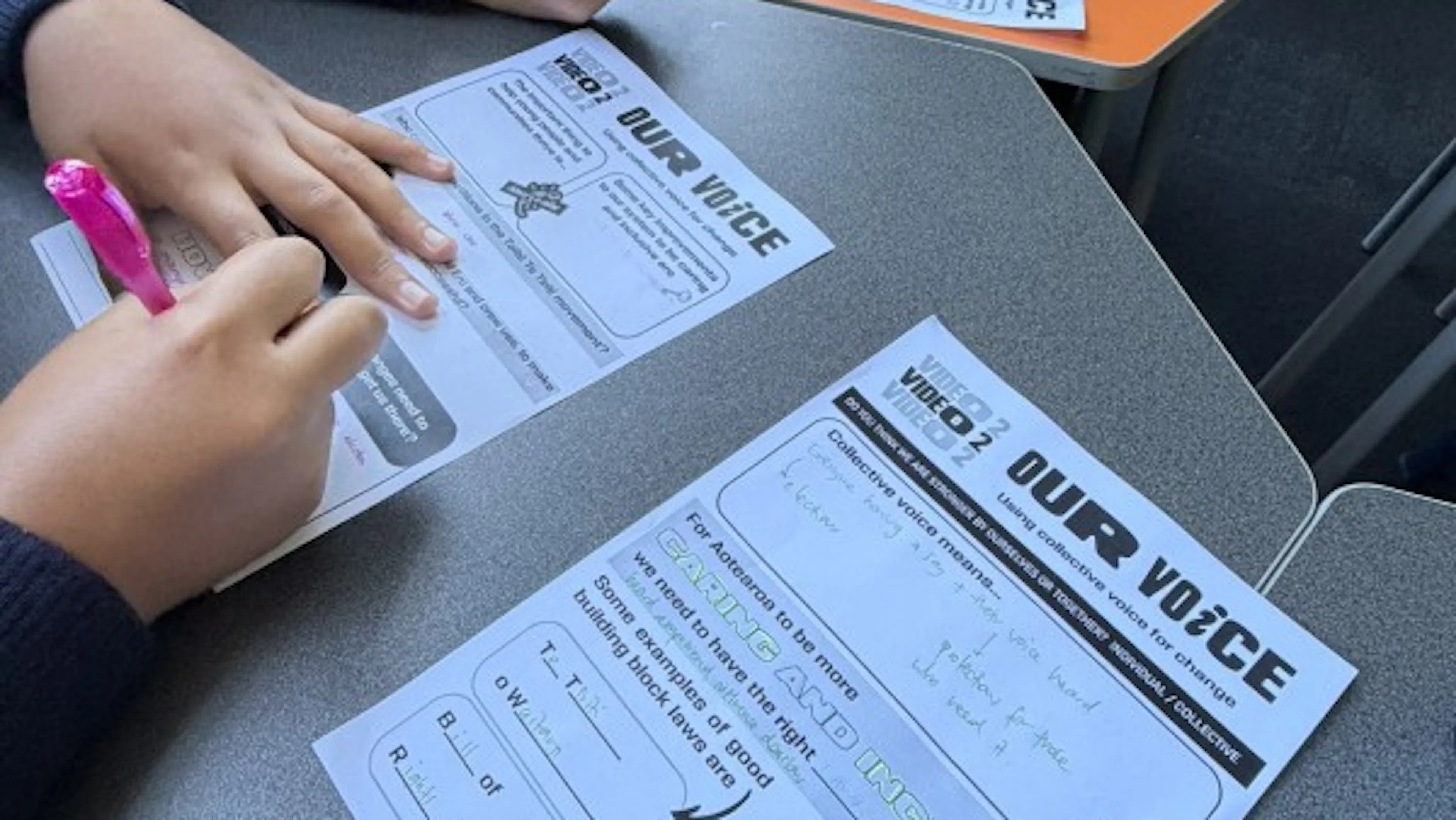 close up of school students filling in Waha worksheets