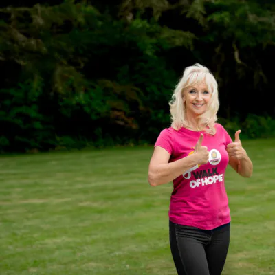 Debbie McGee in pink branded t-shirt with thumbs up