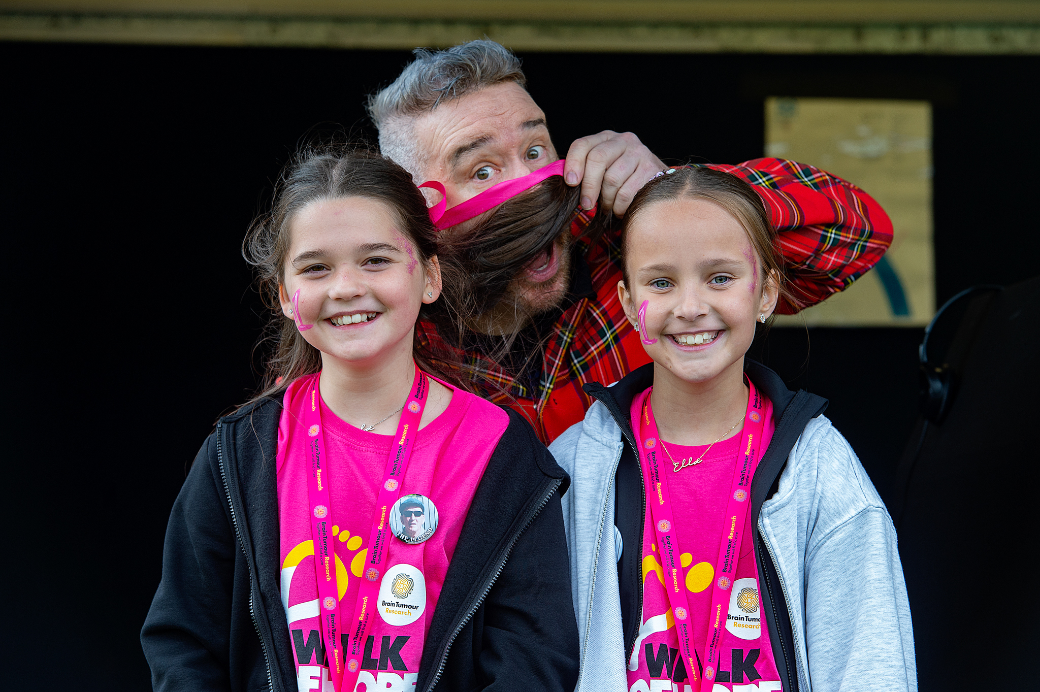 An adult being goofy with two kids in Walk of Hope t-shirts.