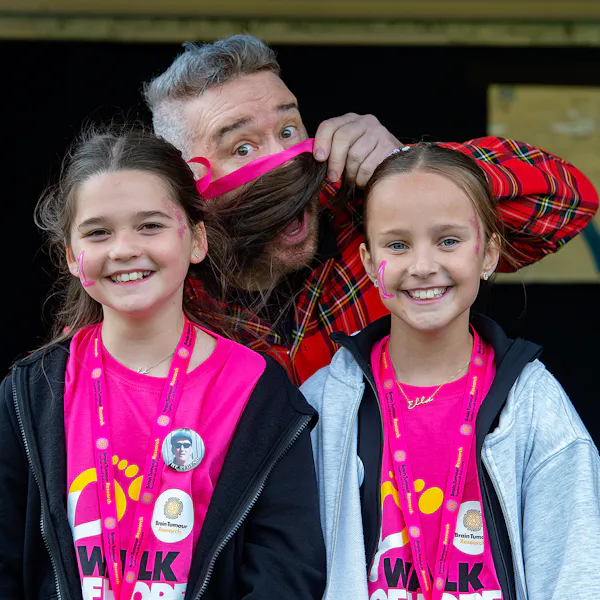 An adult being goofy with two kids in Walk of Hope t-shirts.