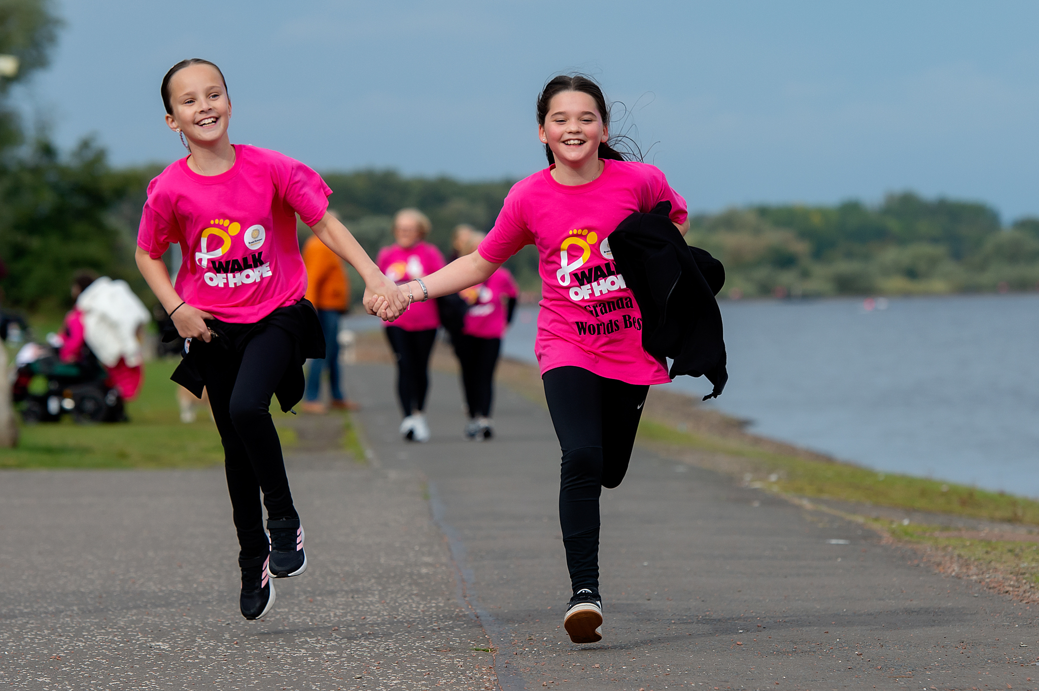 Two kids smiling and running hand-in-hand, wearing Walk of Hope t-shirts. 