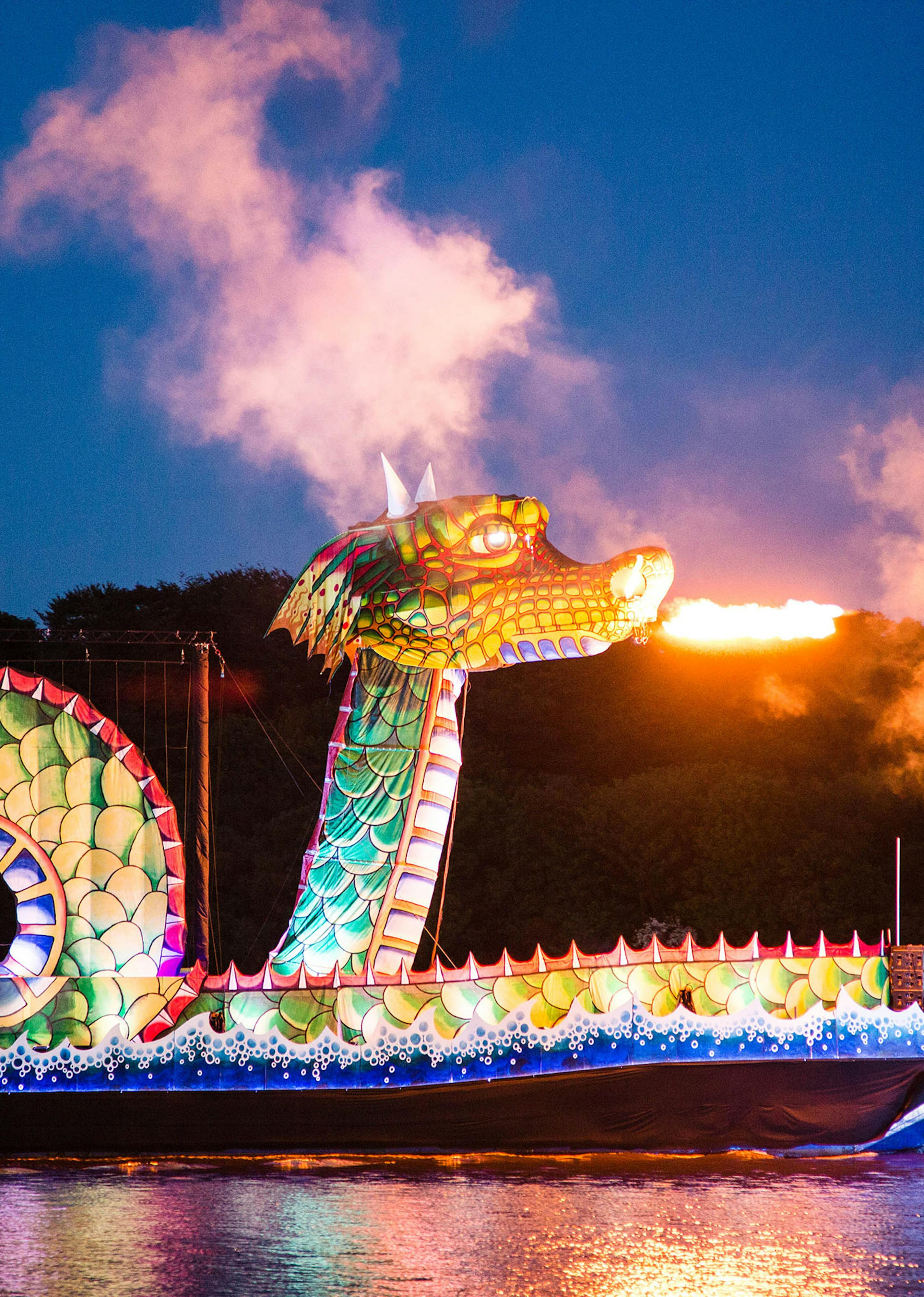 A large green dragon atop of boat breathing fire 