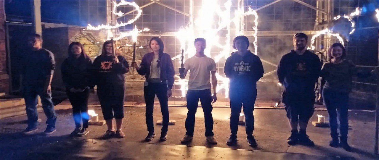 A group of people standing in-front of a wall of fire drawings