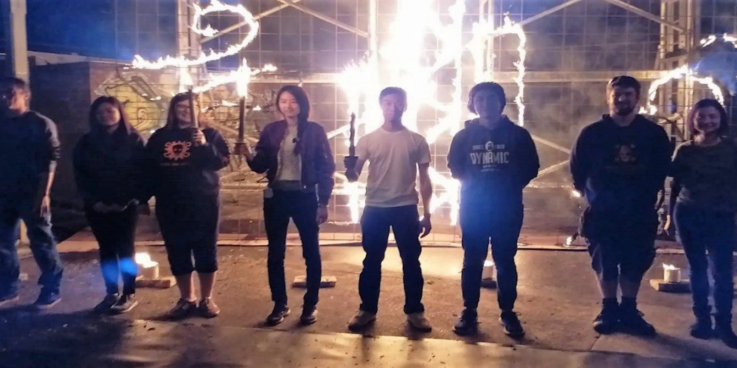 A group of people standing in-front of a wall of fire drawings
