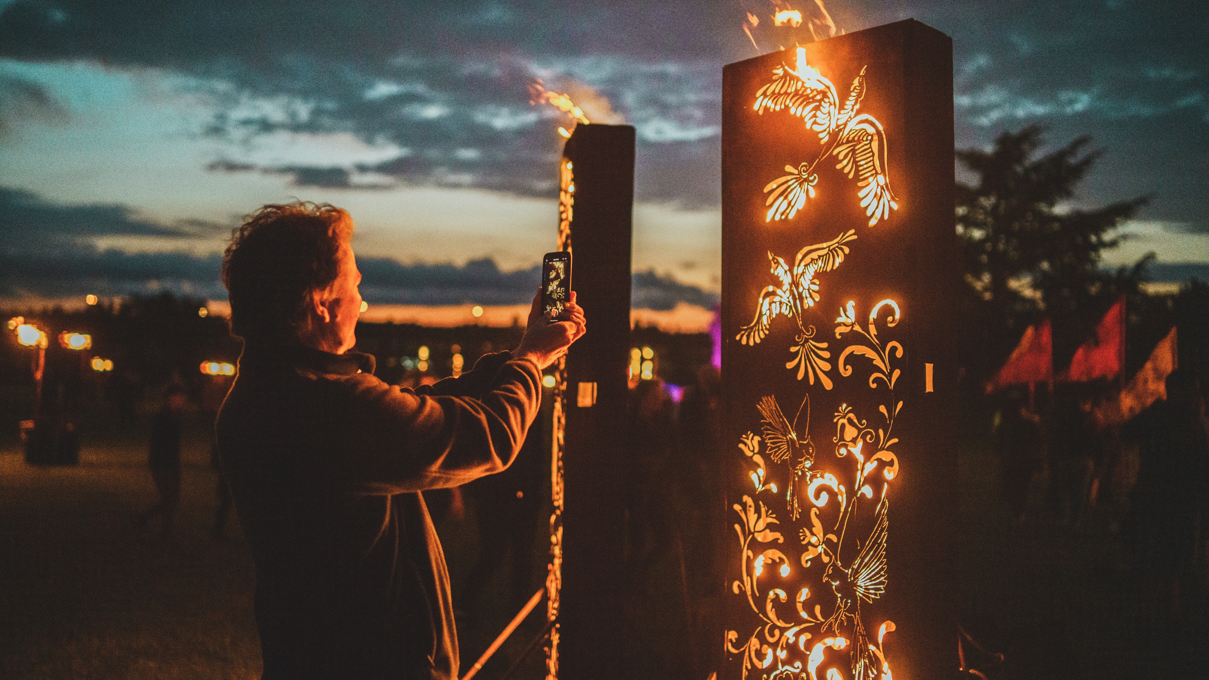 A person taking a photo of intricate fire sculptures