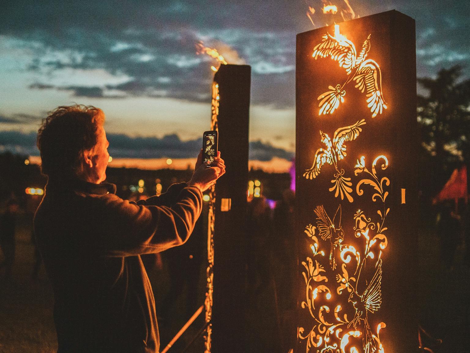 A person taking a photograph of an fire sculpture installation 