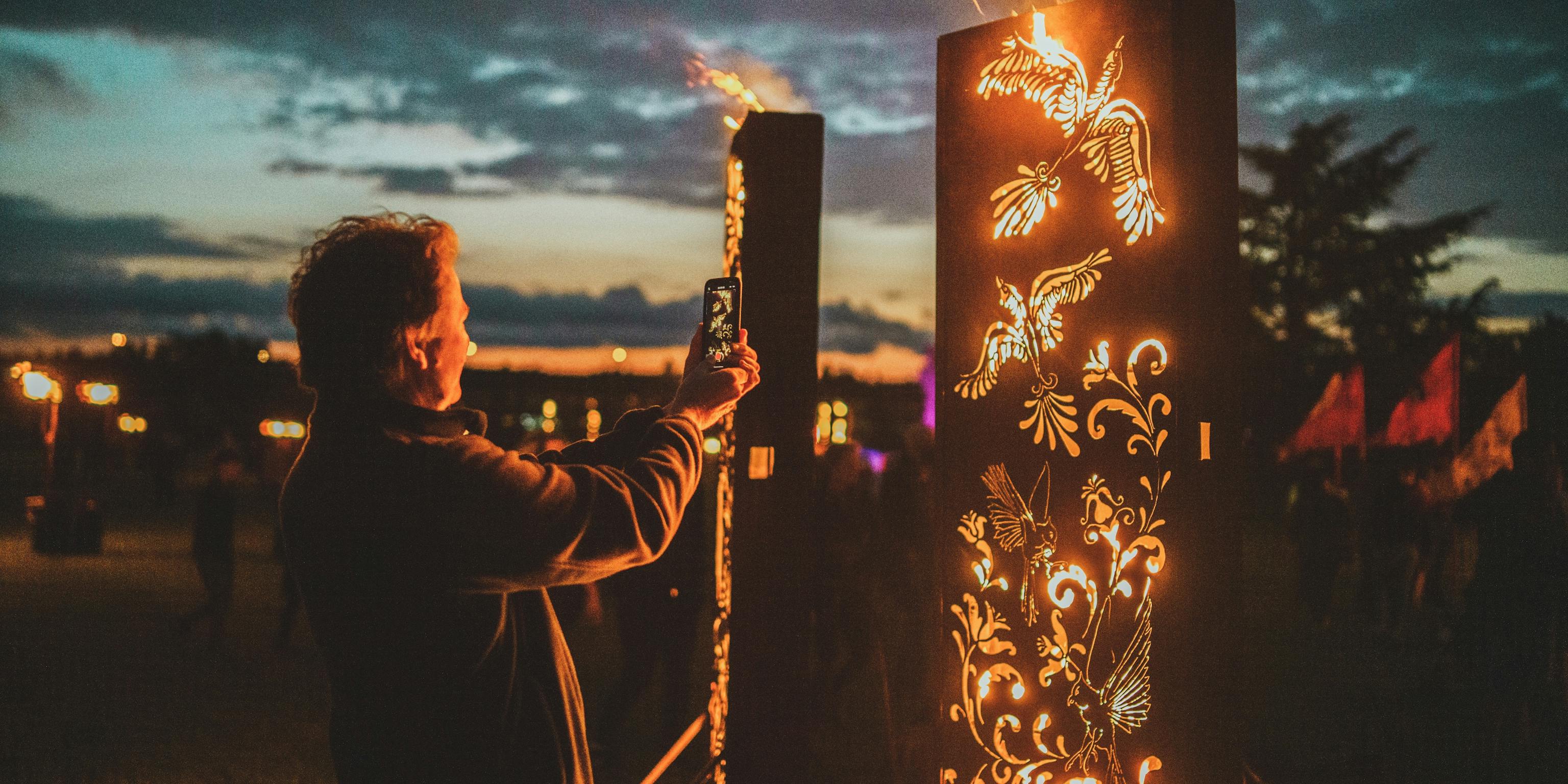 A person taking a photo of intricate fire sculptures