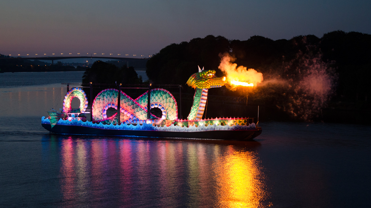 A large green dragon atop a boat breathing fire 