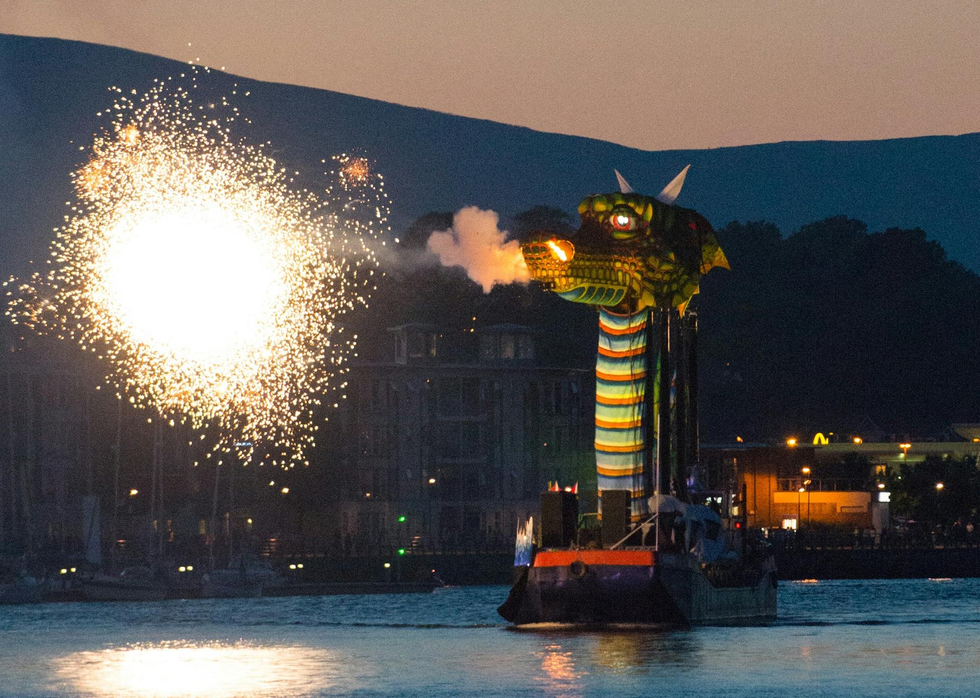 A large green dragon spitting sparks as it travels on the water