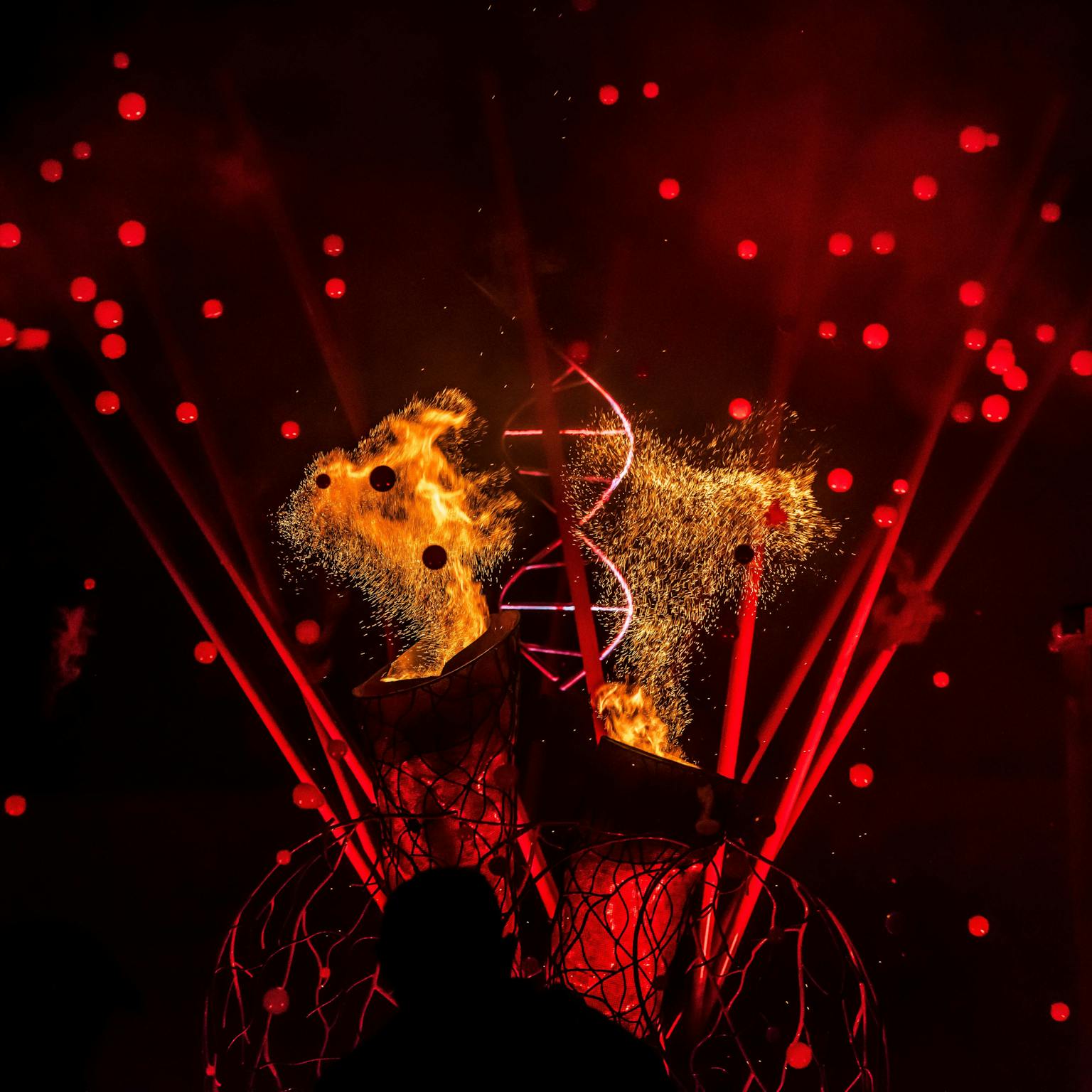 A structure of an organ heart lit in red with pyro and glowing red bubbles in the background. 