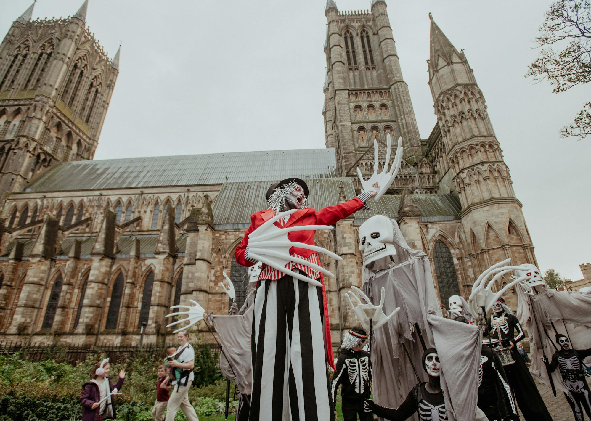 A group of performers dressed with ghost puppets performing in front of a cathedral 