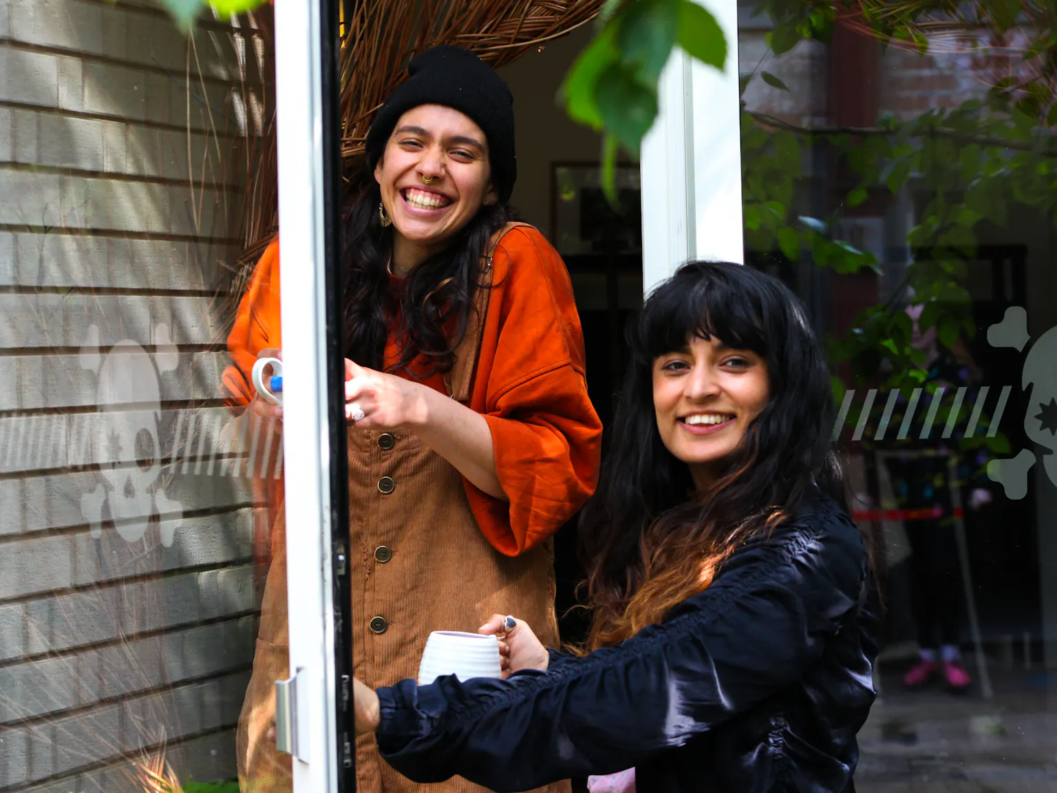 Two people smiling with tea cups in their hands