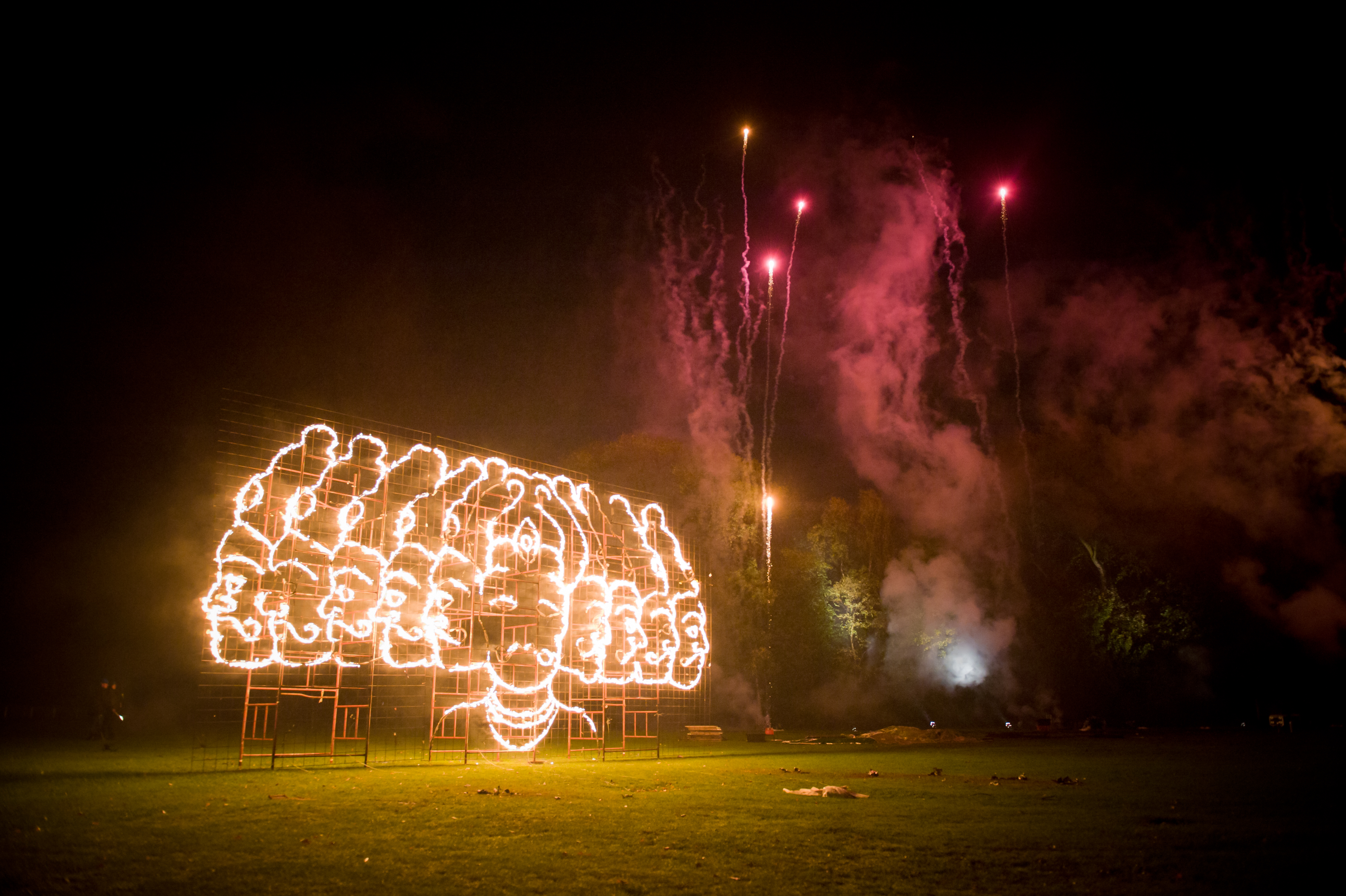 Fireworks above a fire drawing of a multi-headed person