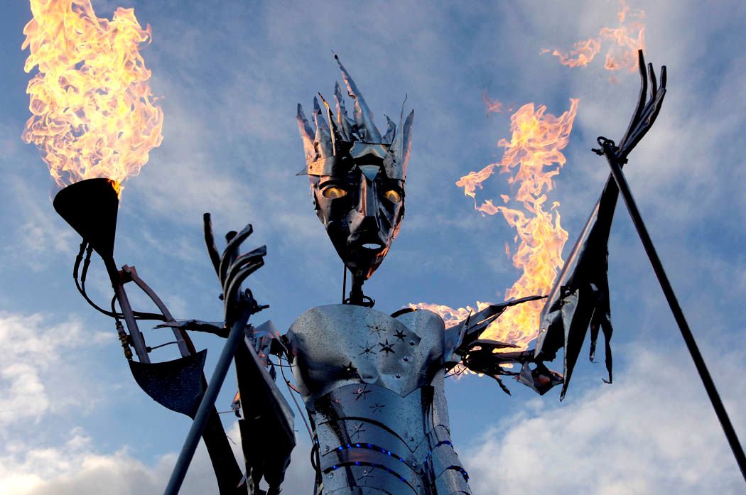 A steel ice queen puppet with glowing eyes and fire coming out of her arms.