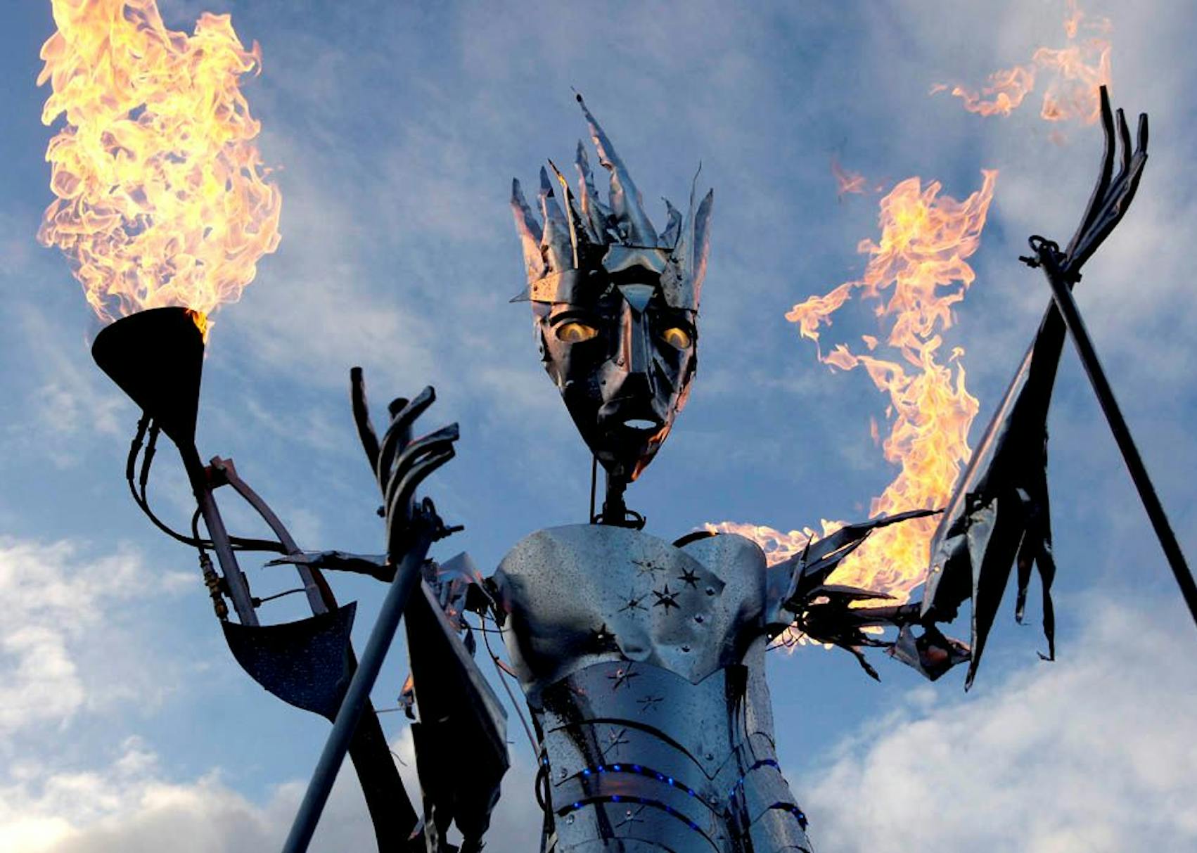 A steel ice queen puppet with glowing eyes and fire coming out of her arms.