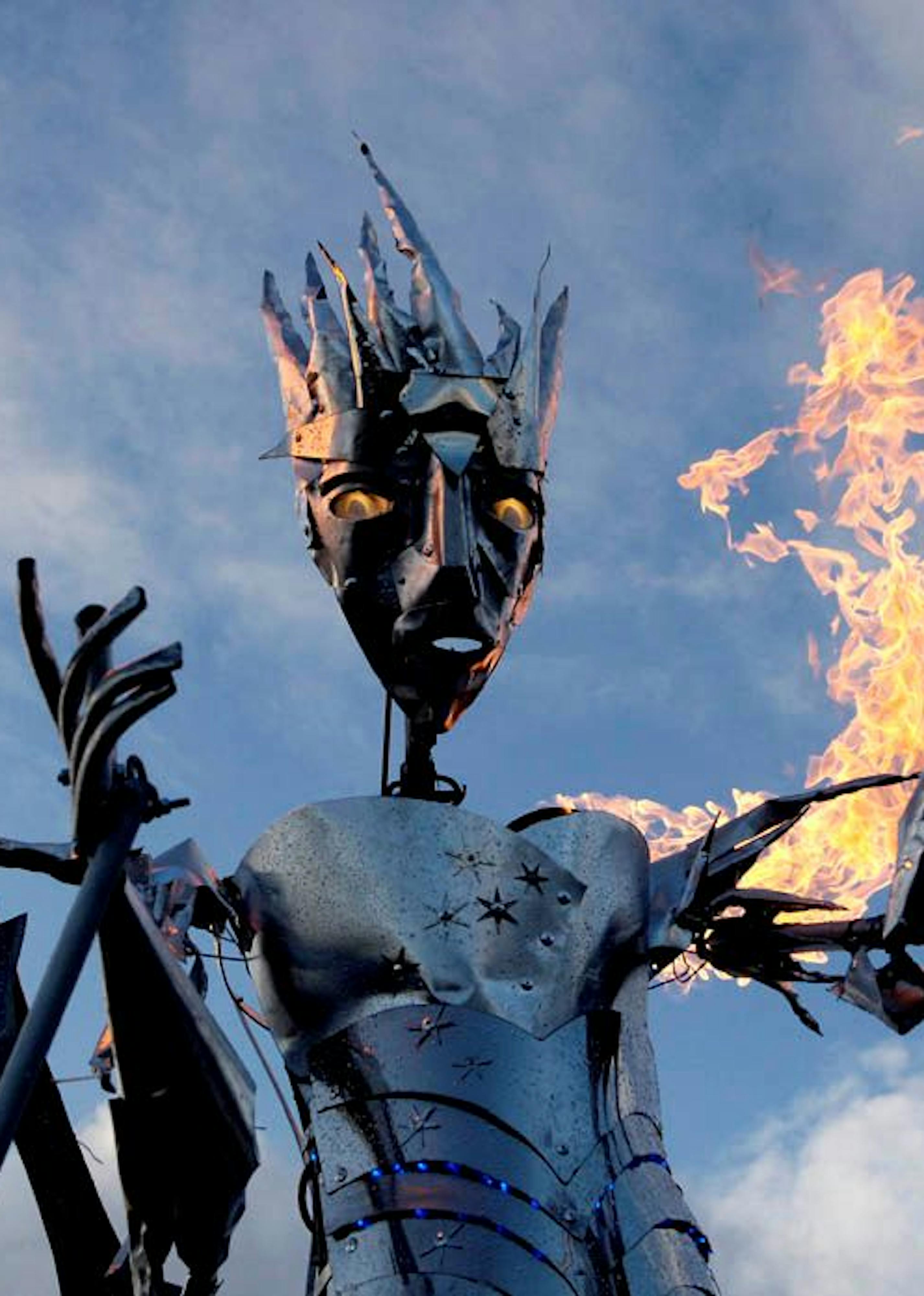 A steel ice queen puppet with glowing eyes and fire coming out of her arms.