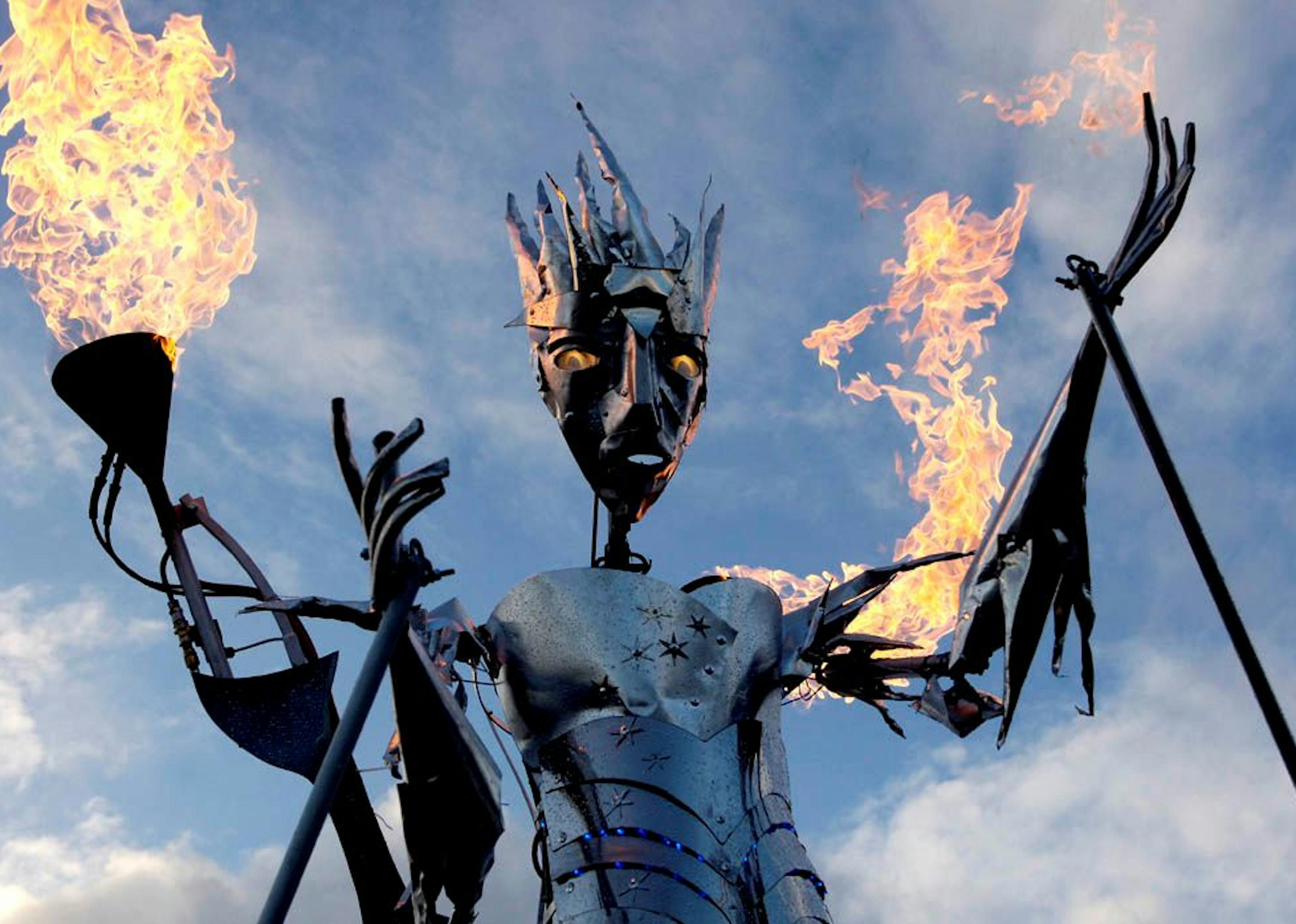 A steel ice queen puppet with glowing eyes and fire coming out of her arms.