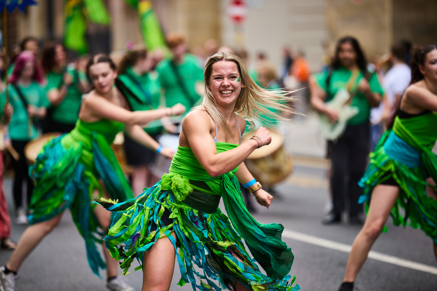 A person dressed in a green dress dancing in a parade