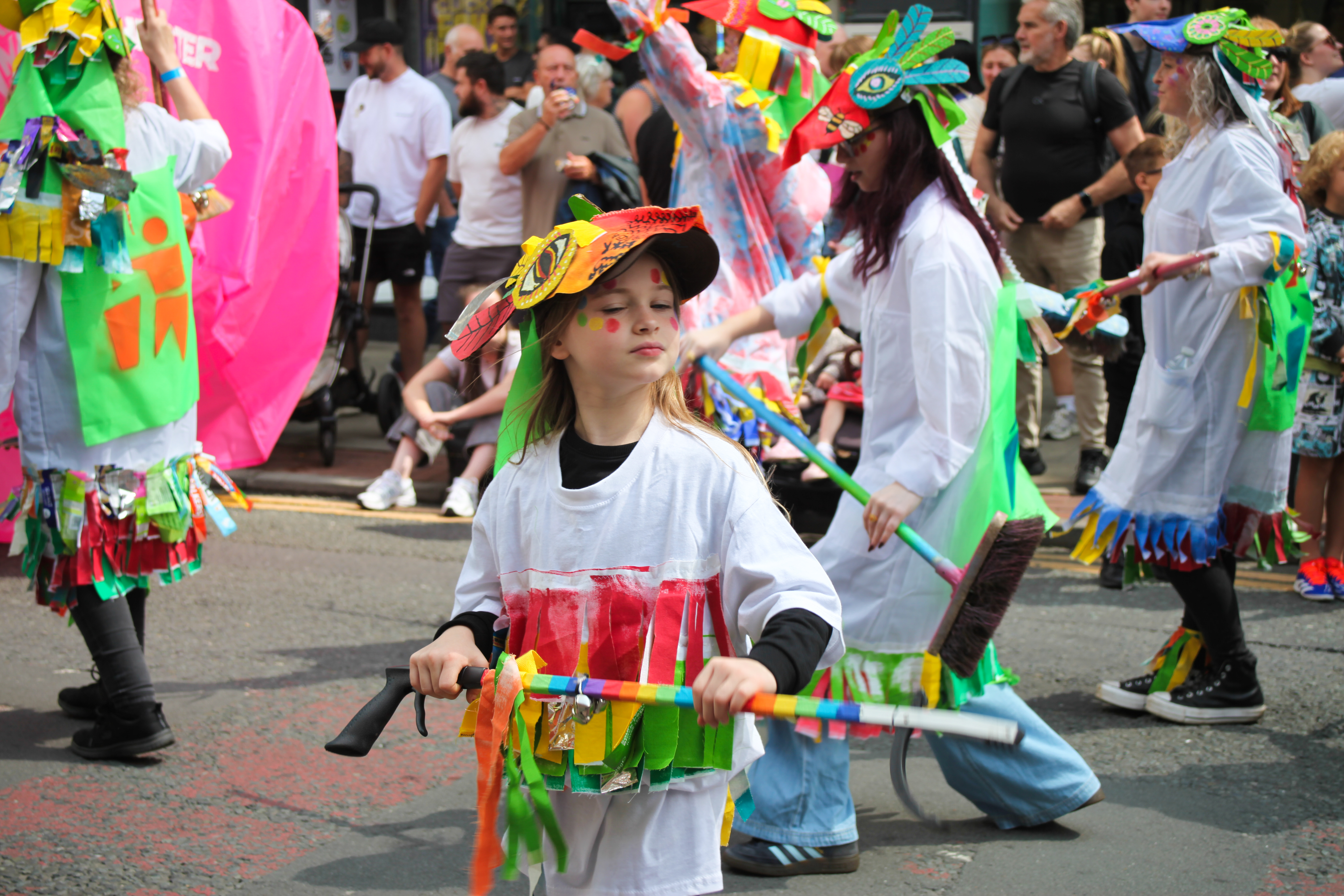 A young girl dressed in a handmade colourful costume in a parade. 
