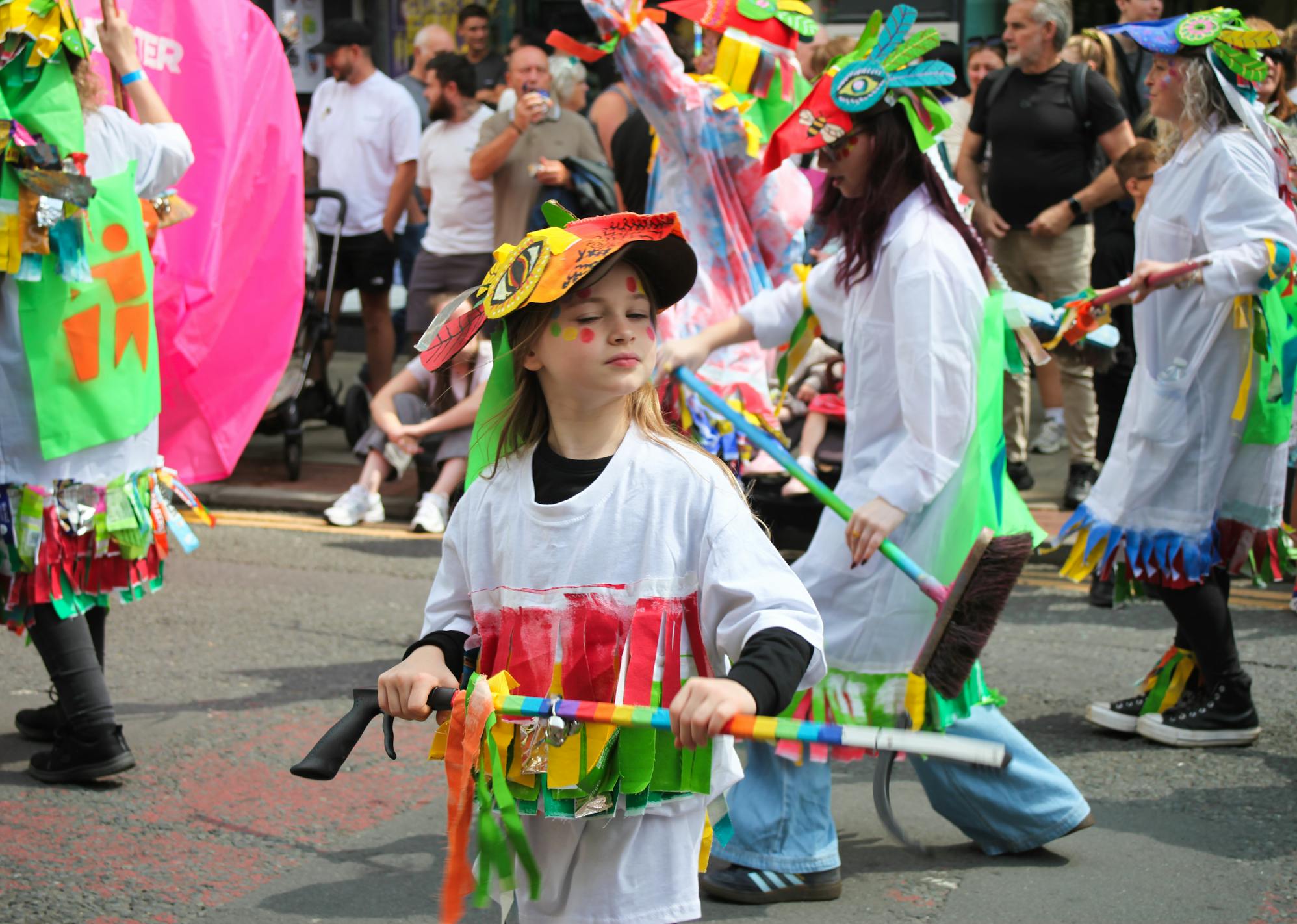 A young girl dressed in a handmade colourful costume in a parade.