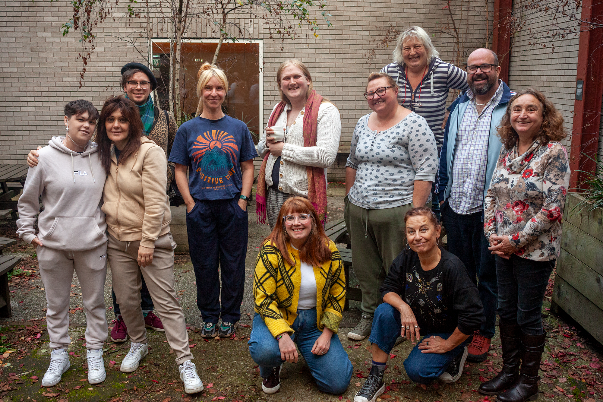 A group photo of 11 people posing together in an outside courtyard