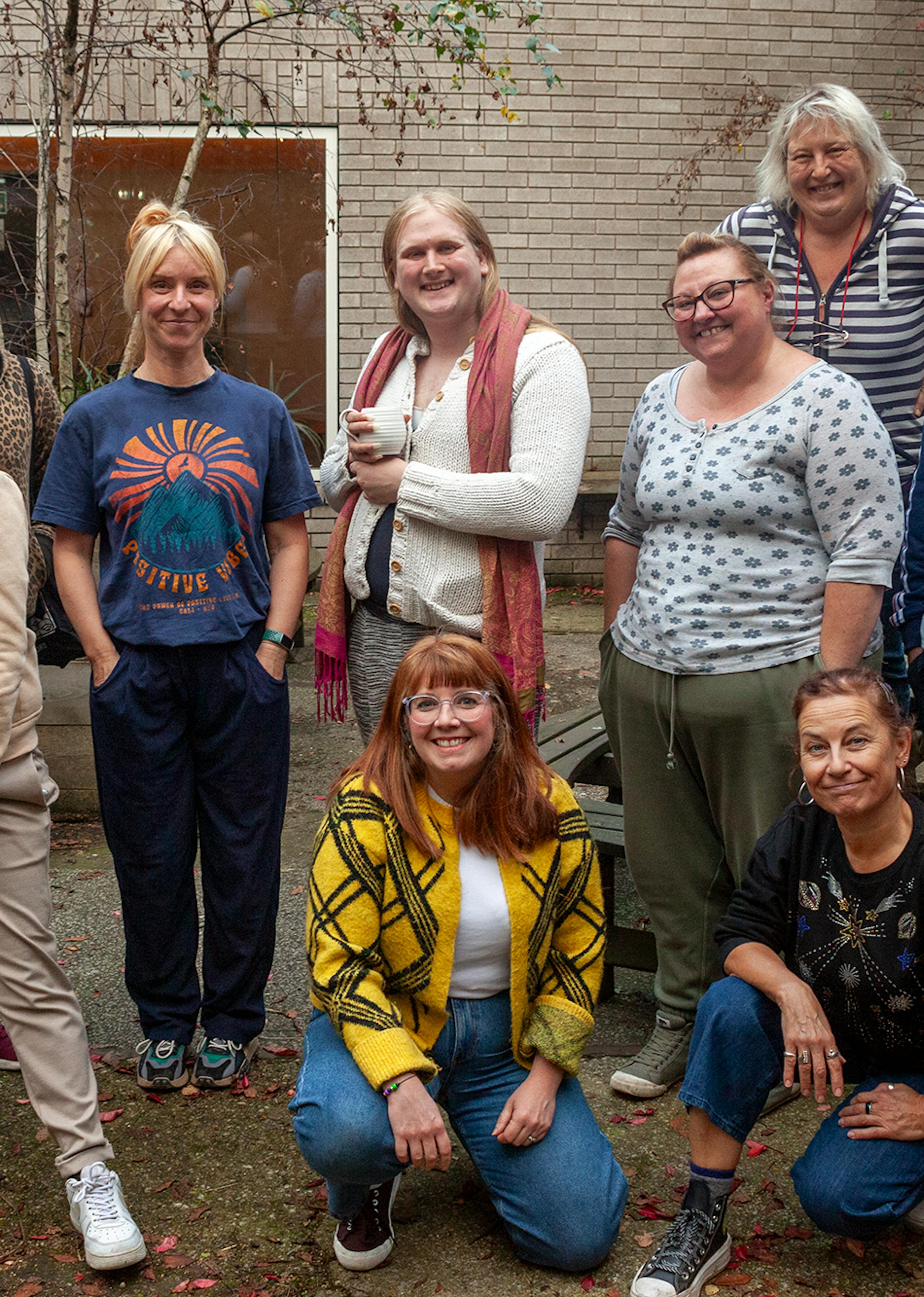 A group photo of 11 people posing together in an outside courtyard