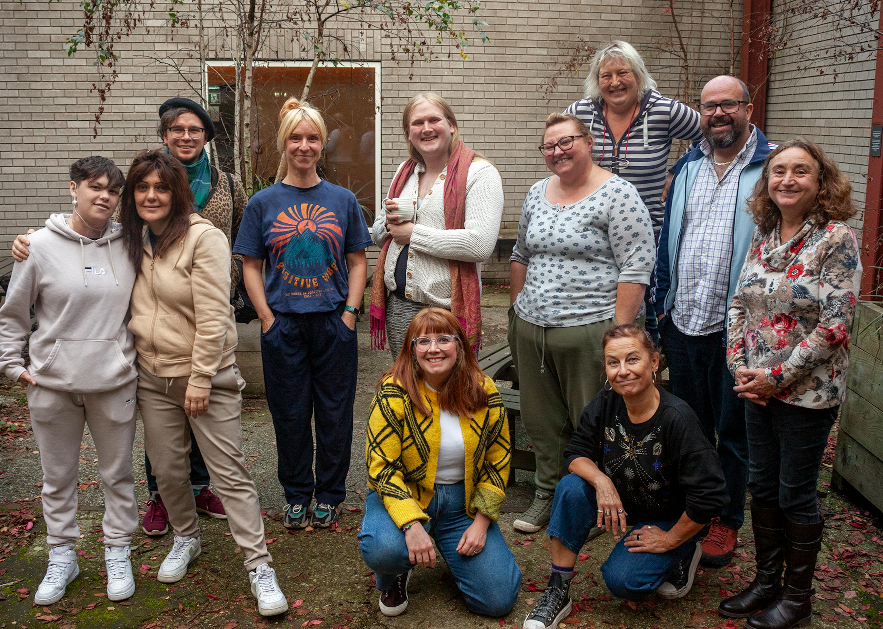 A group photo of 11 people posing together in an outside courtyard
