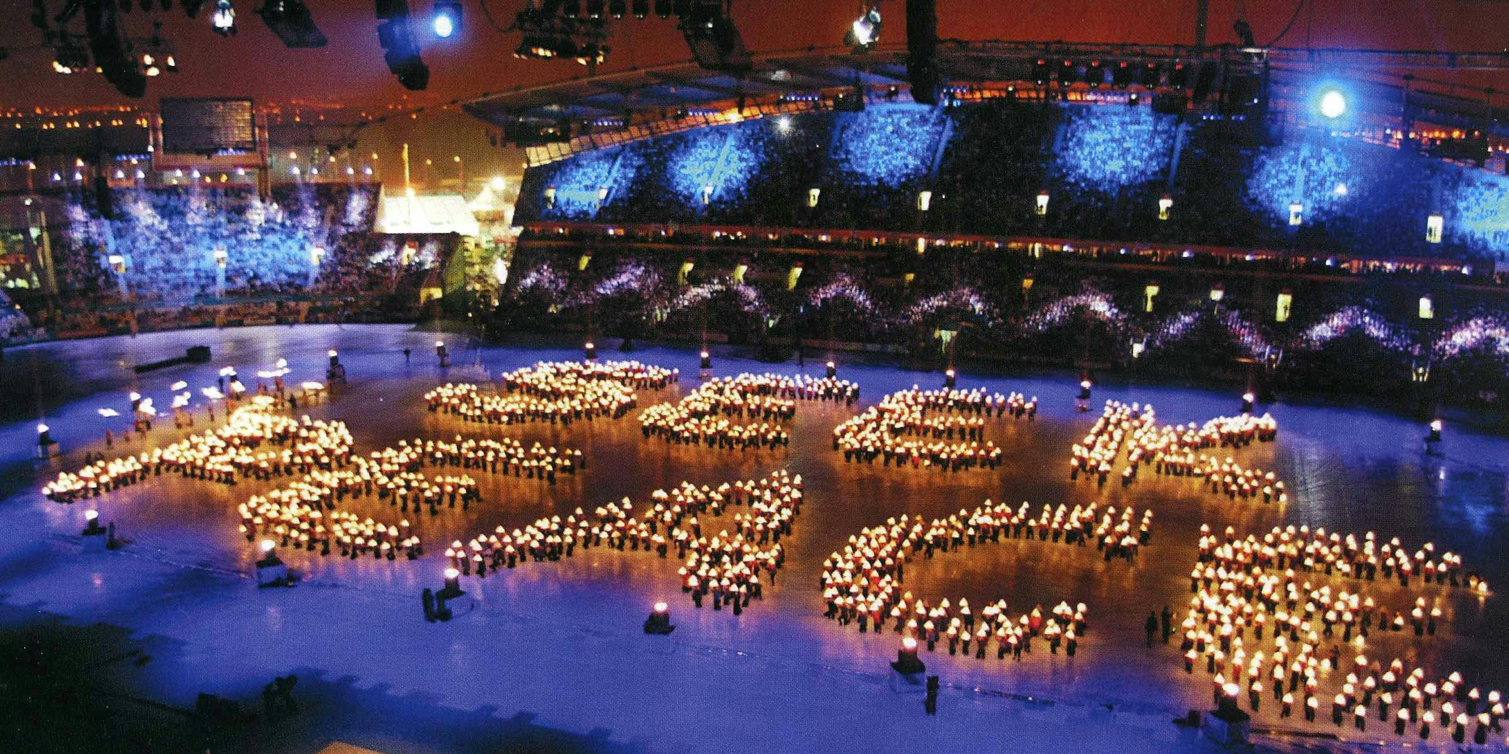 Hundreds of lanterns in the centre of an arena spelling out the words 'Seek Peace'