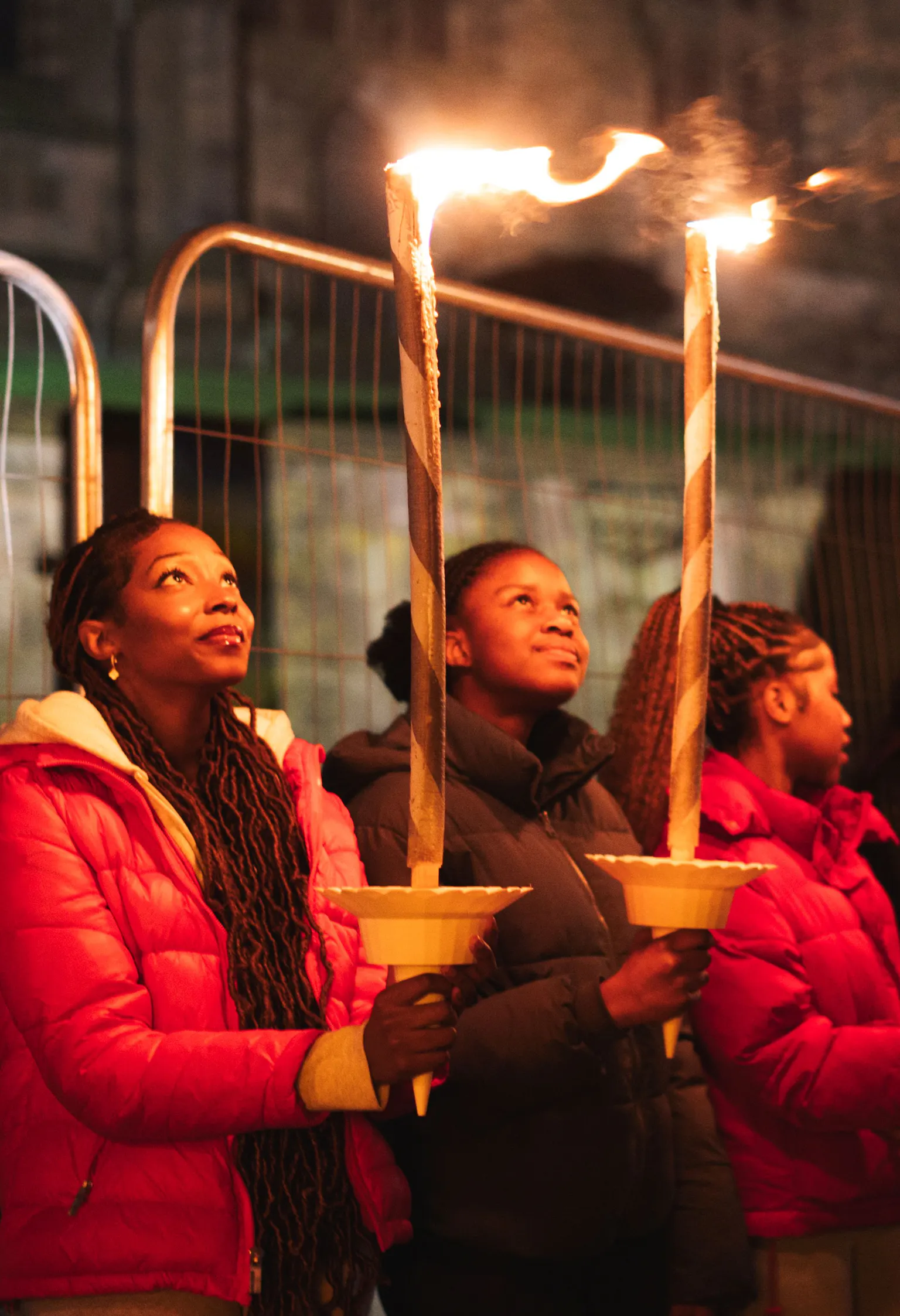 Group of people holding lit torches during a nighttime vigil or ceremony outdoors.