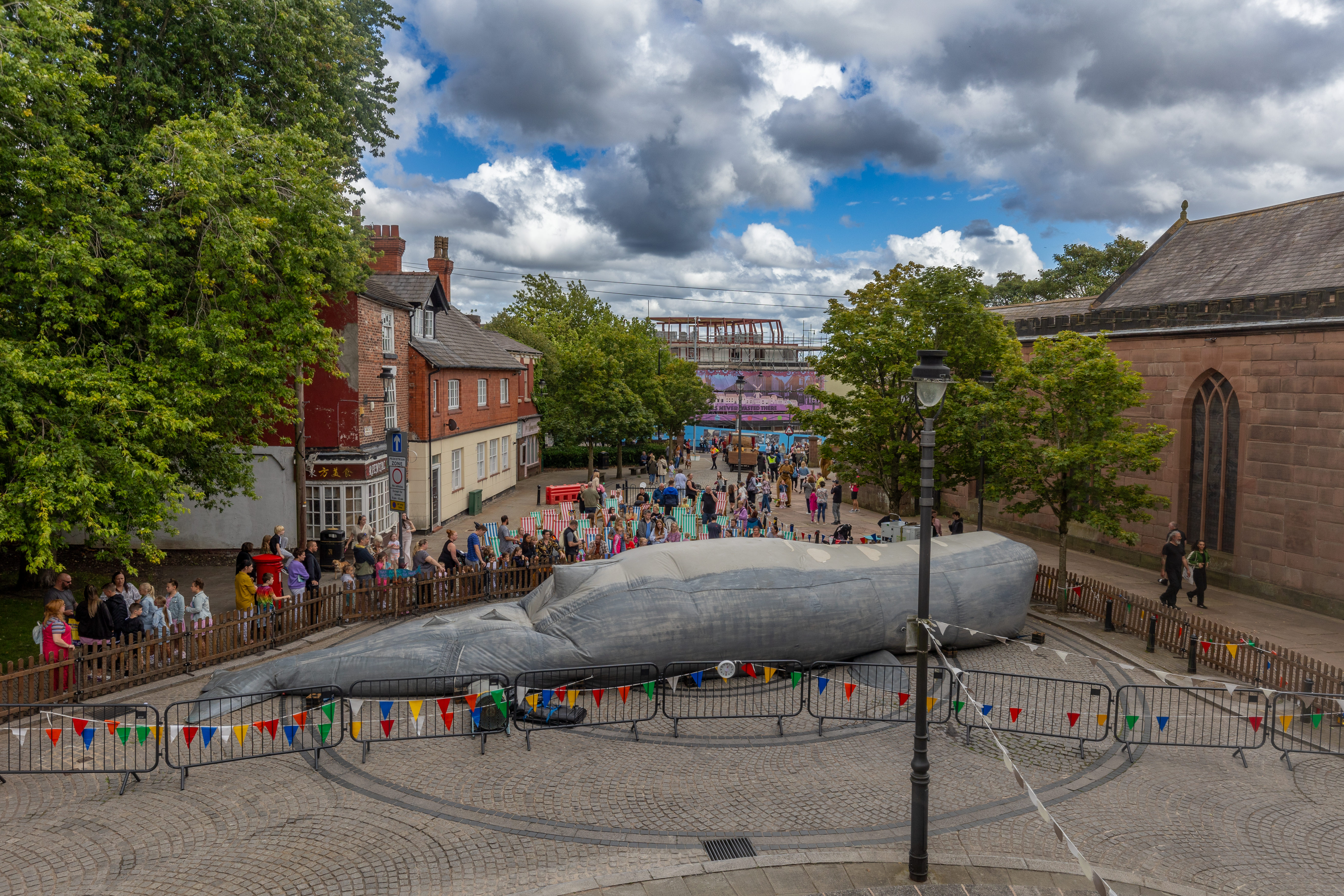 A giant 50-foot sperm wale installation in a town centre surrounded by bunting and people lining up to enter 