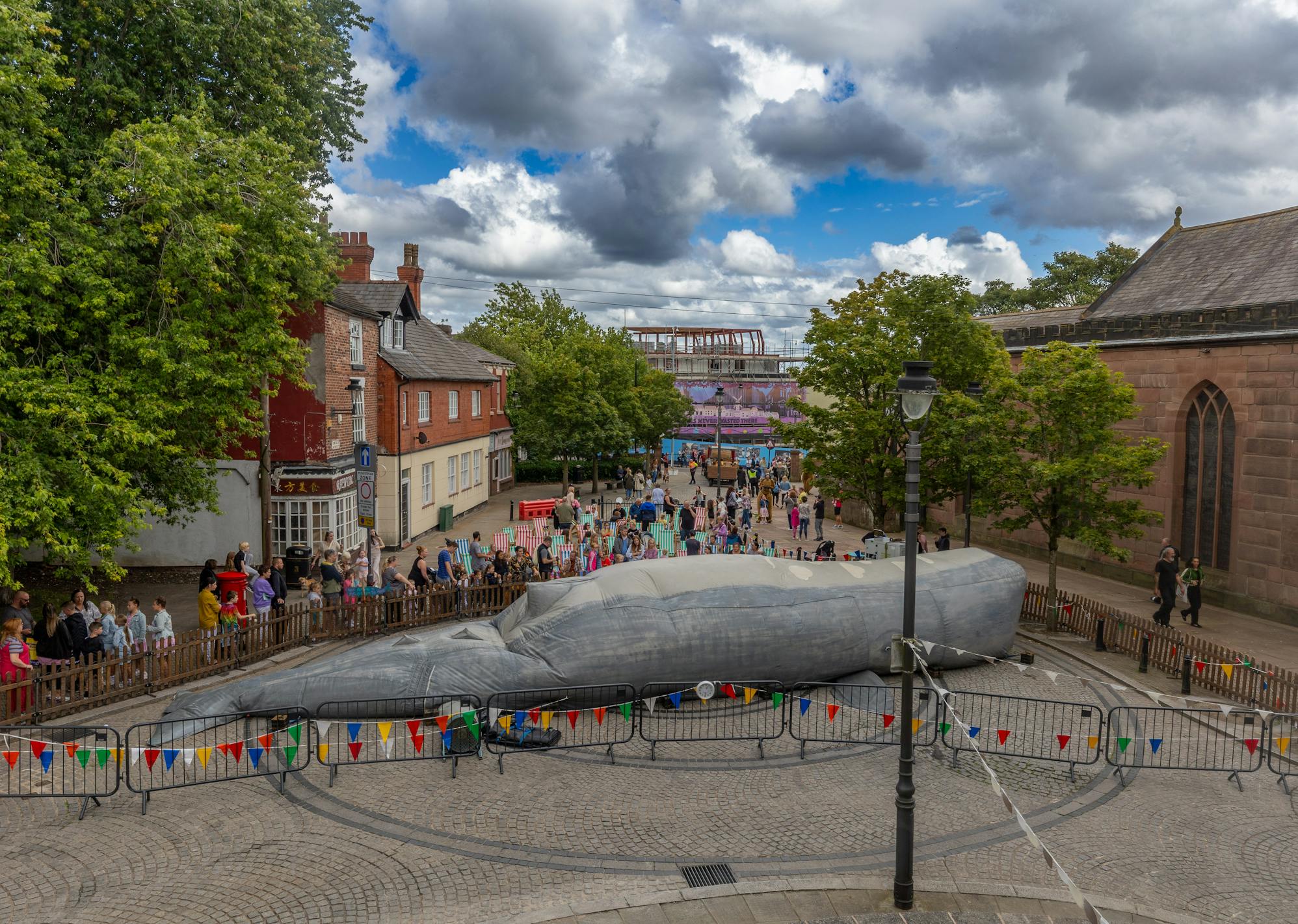 A giant 50-foot sperm wale installation in a town centre surrounded by bunting and people lining up to enter