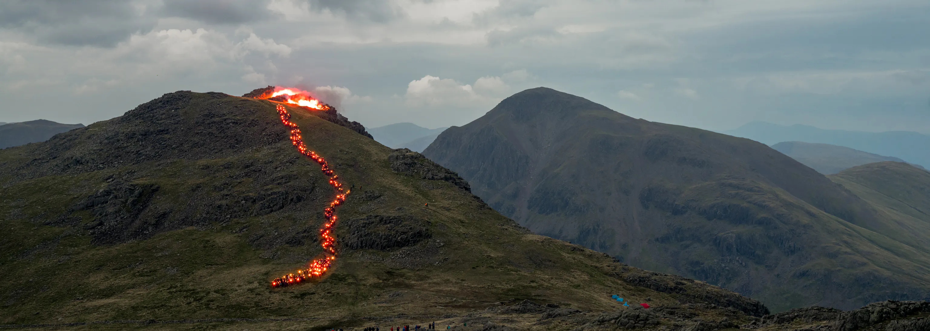 A foggy mountain top with a trail of red lights snaking down to simulate lava flow