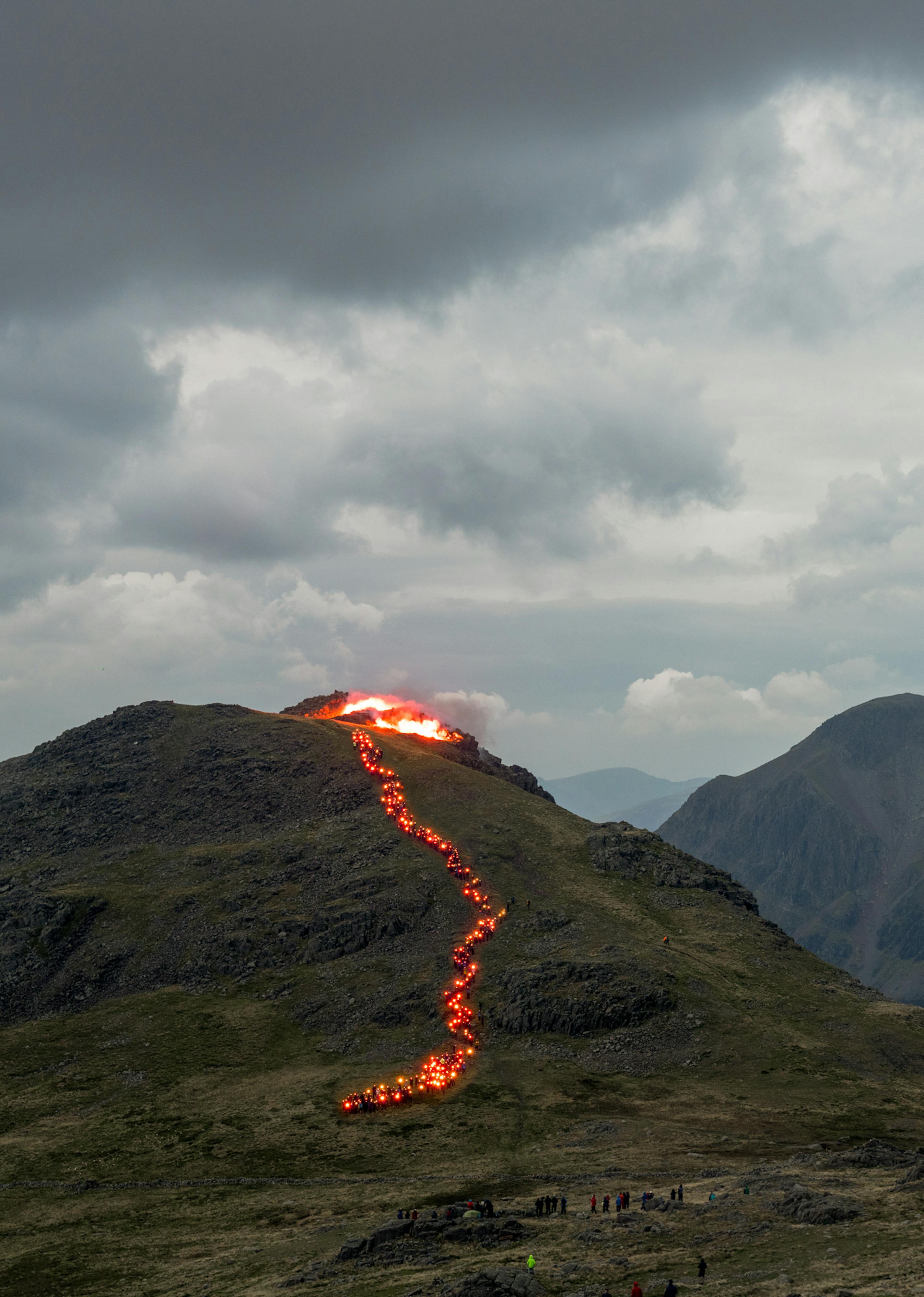 A foggy mountain top with a trail of red lights snaking down to simulate lava flow