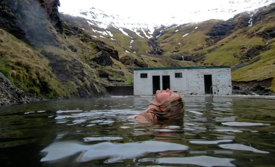 woman swimmiing in iceland's oldest swimming pool in the mountains