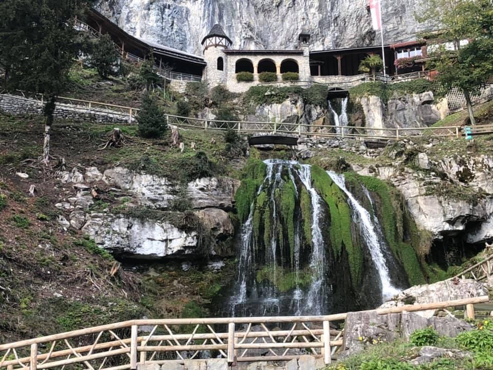 Castle on the side of a moutain with a waterfall below it