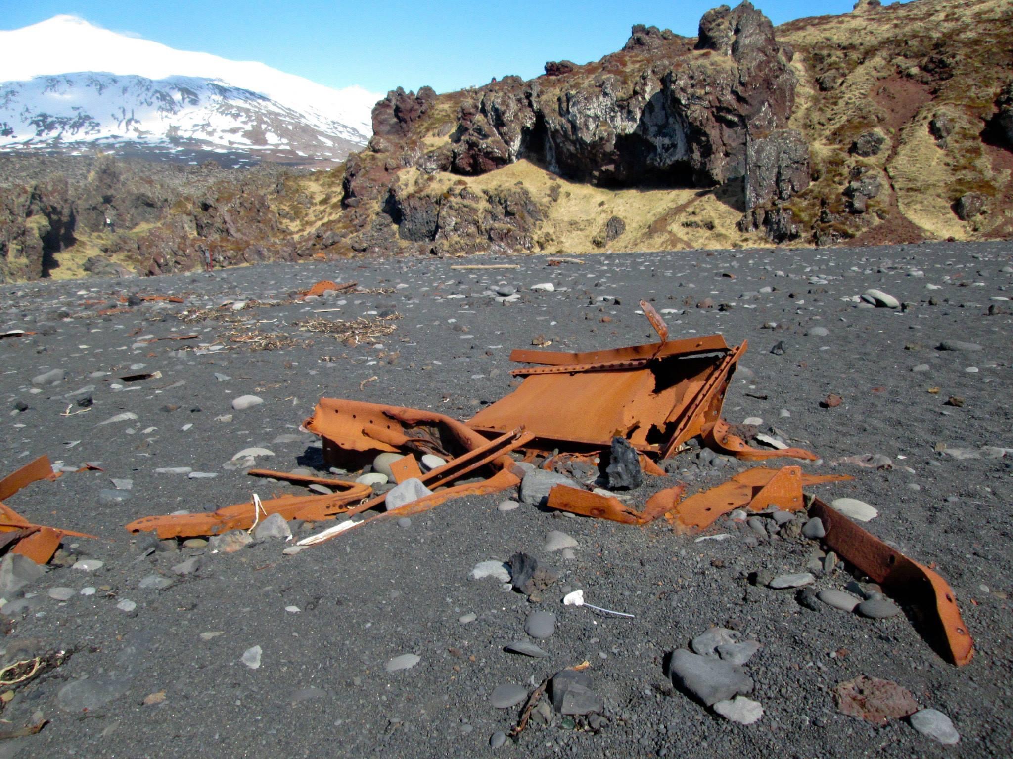 Metal boat scraps on black sand beach