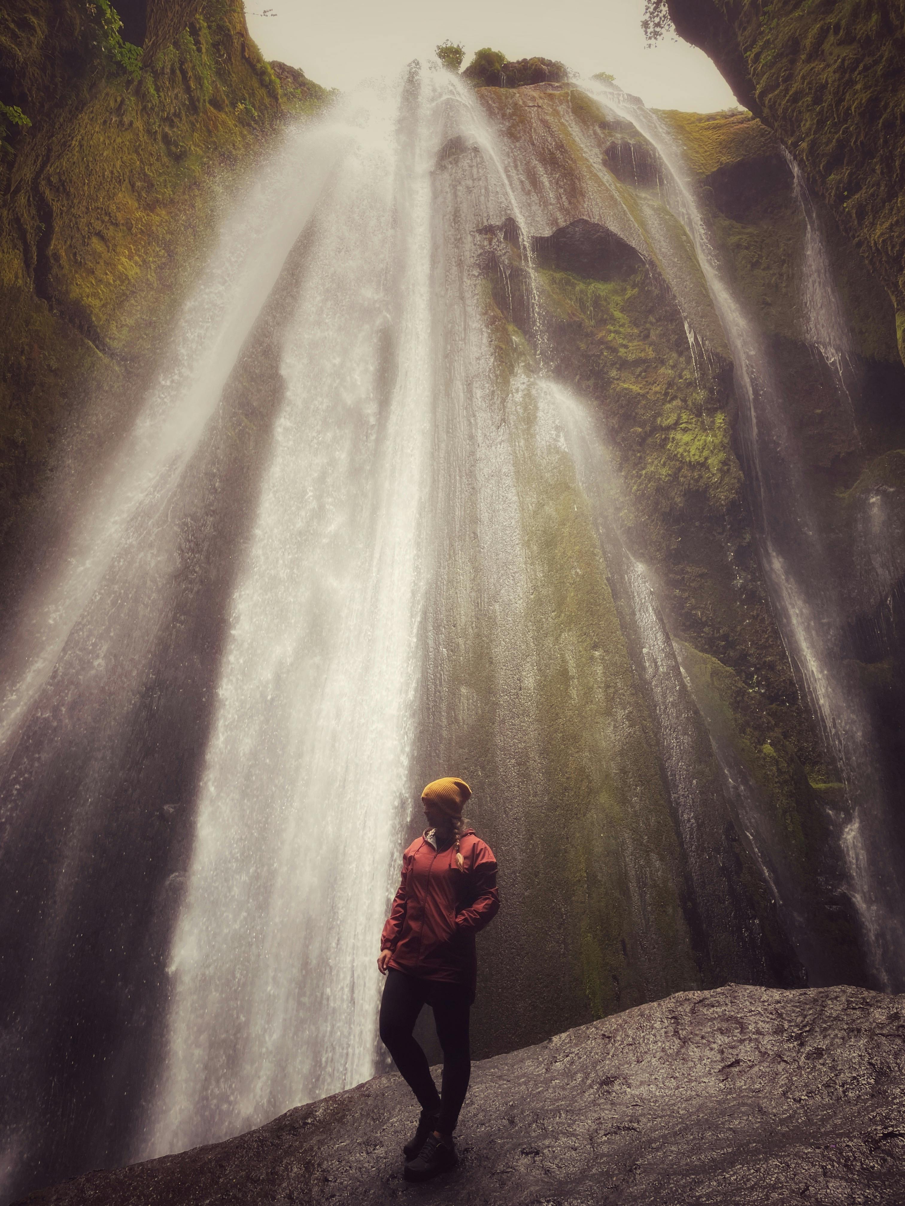 woman standing at the bottom of Gljúfrabúi Waterfall