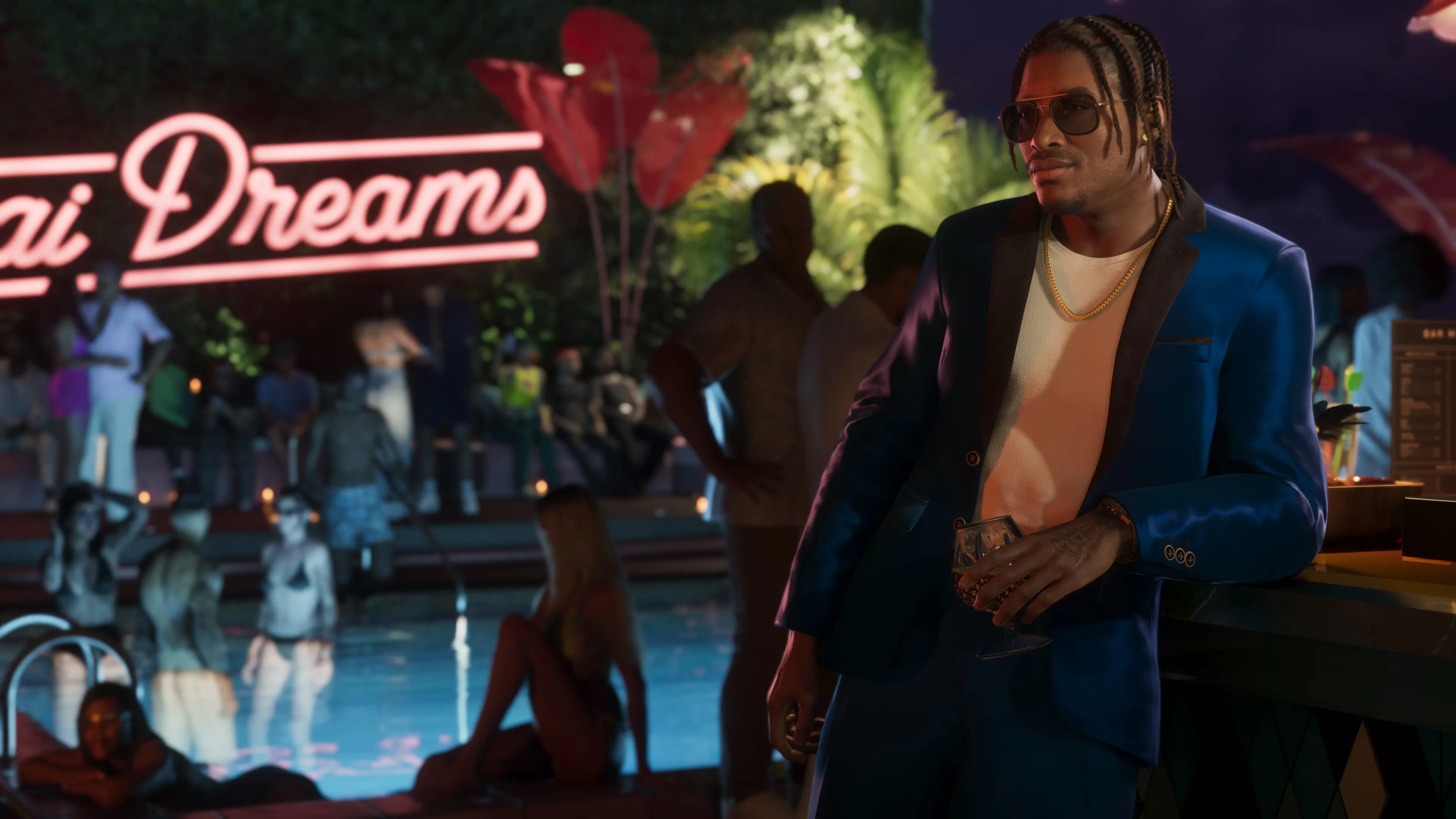 Dre'Quan Priest in a blue suit and sunglasses, glass in hand, leaning on a bar by a pool at night.