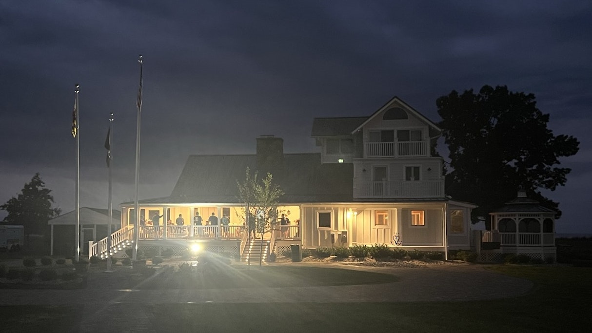 Nighttime, from a distance, the main house of Patriot Point is in frame with the Marines of 1st Platoon CLR 15 just visible using the porch to share stories and remember.