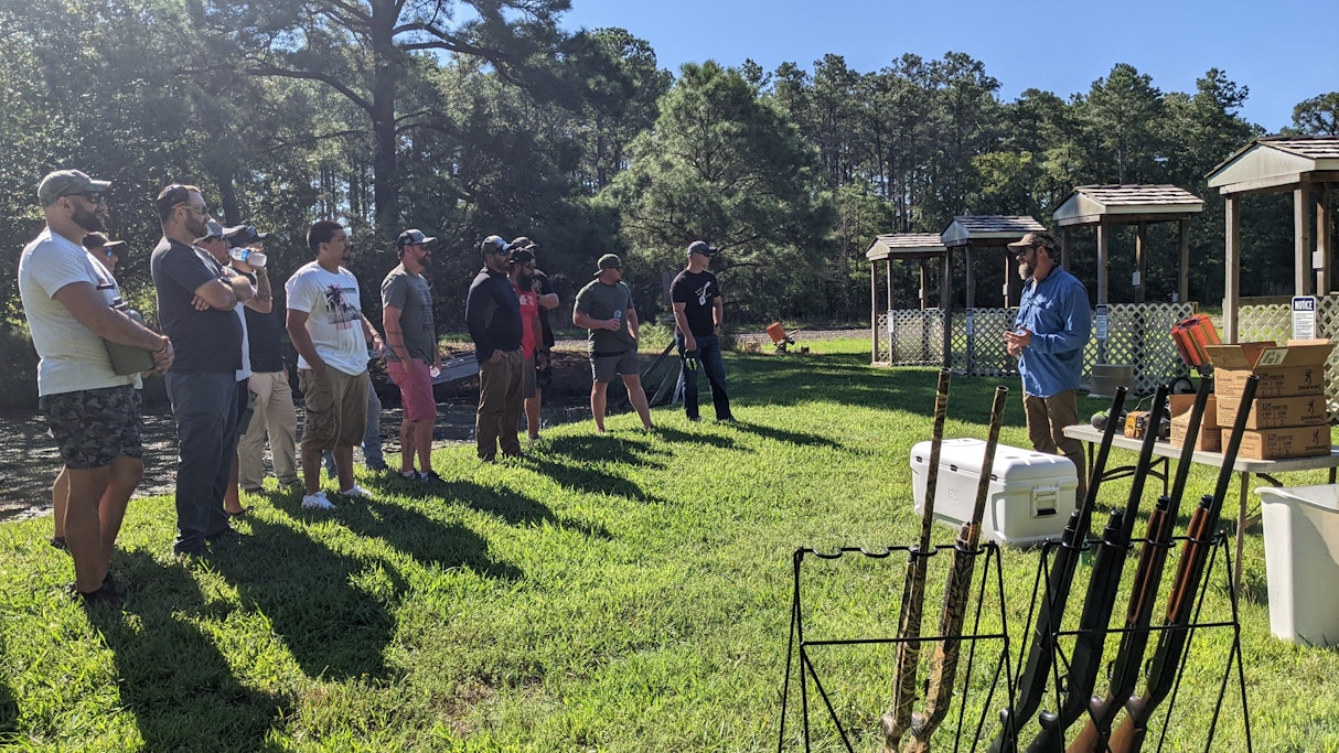 12 Marines from 1st Platoon CLR 15 stand abreast, shotguns in the foreground, the Marines are listening to a safety brief from Hugh Middleton of Patriot Point prior to shooting clay pigeons.