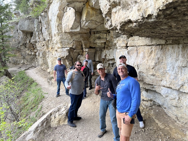 On a narrow trail, against a rockface, soldiers of Creek 2-4 casually pose for a photo while hiking in Sluice Boxes State Park