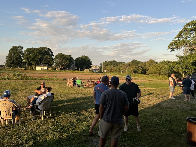 Outside, the sun low in the sky, members of WRF and the local community of Southold, NY, mingle while the soldiers of 1-172 catch up around the fire in the background.