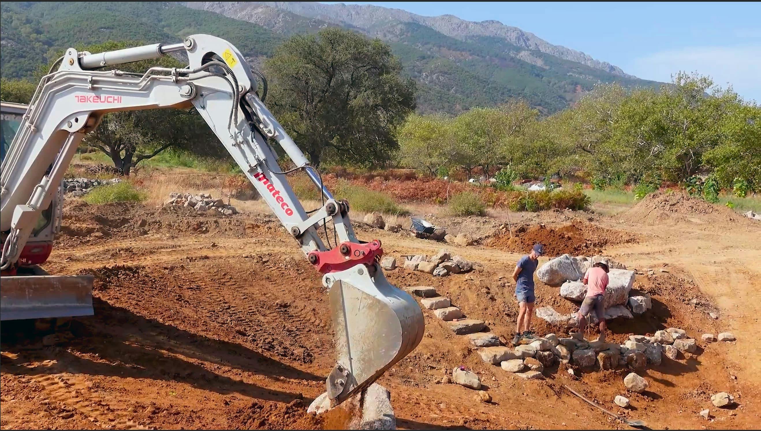 An excavator performs earthworks while constructing a water retention feature