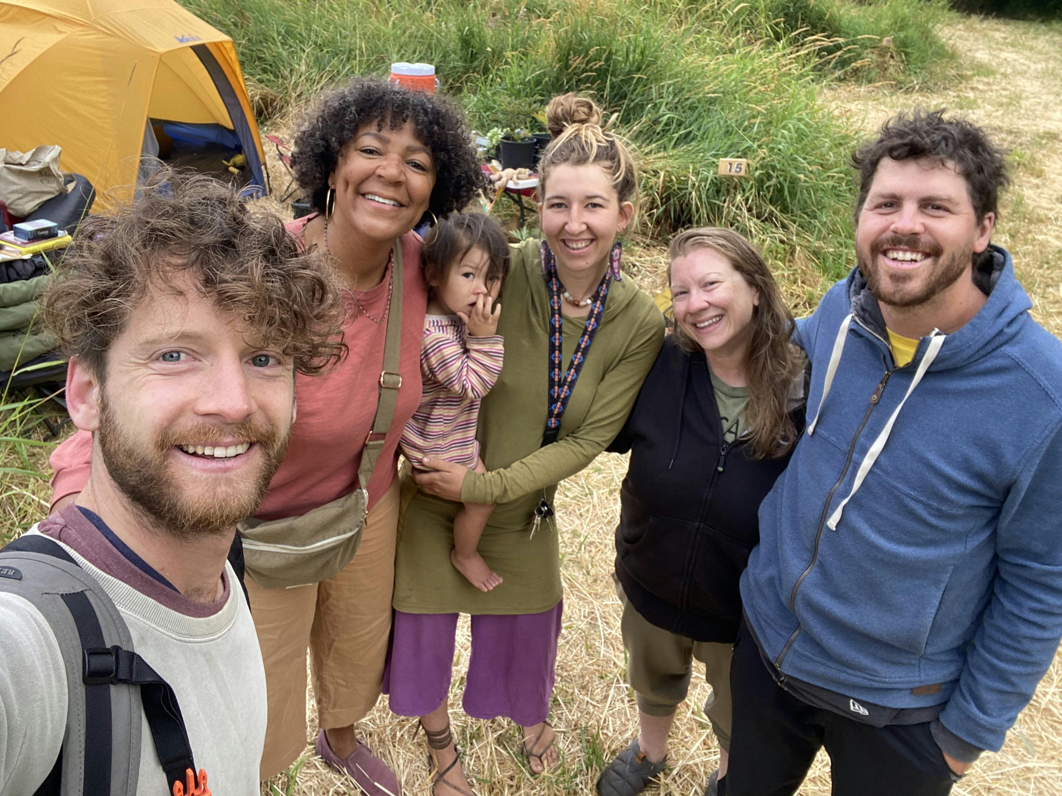 Group selfie of Zach Weiss and Water Stories students at the camp site of a workshop with a tent in the background