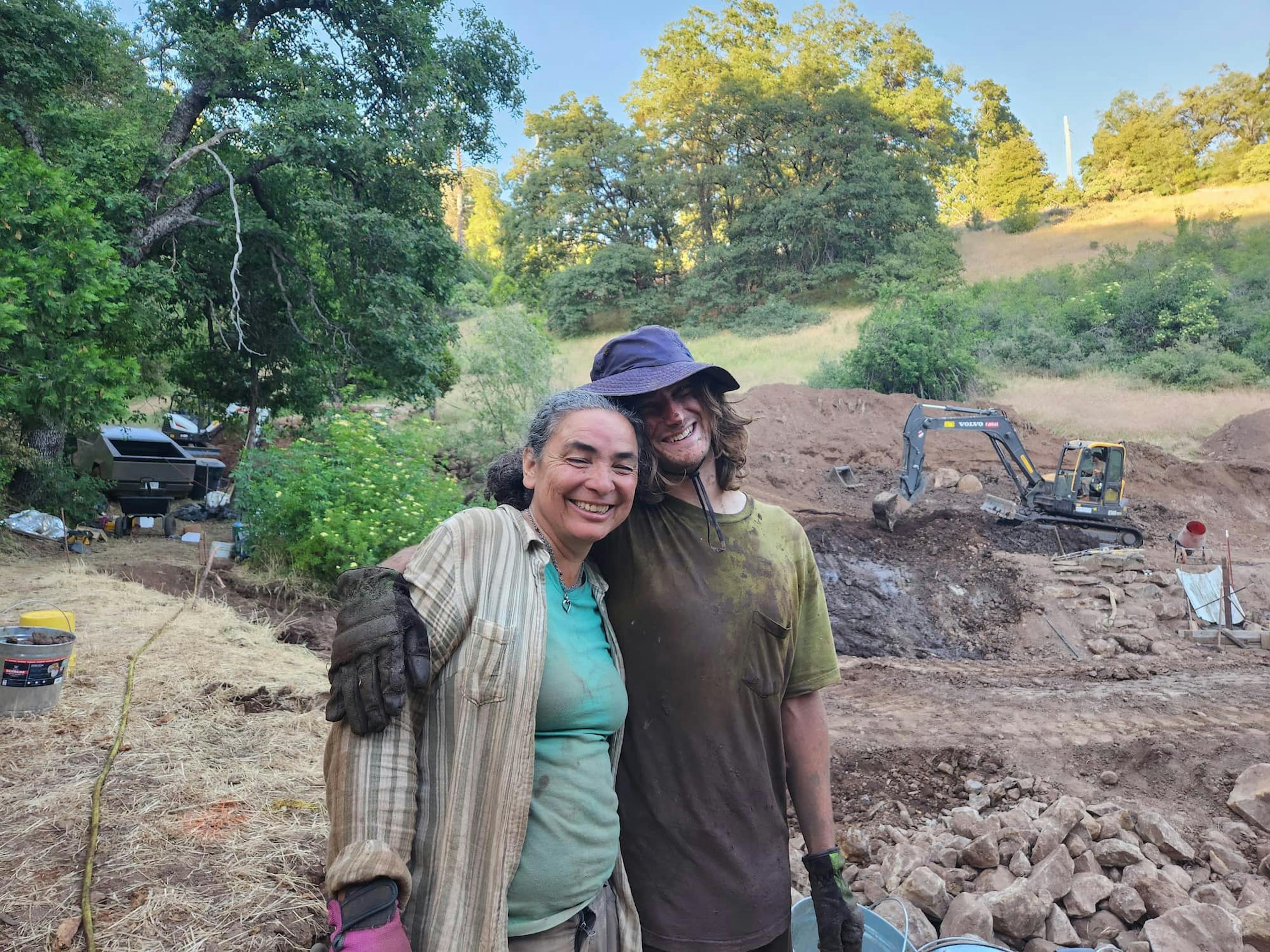 2 Water Stories students, dirty, hugging, and smiling after a hard day's work