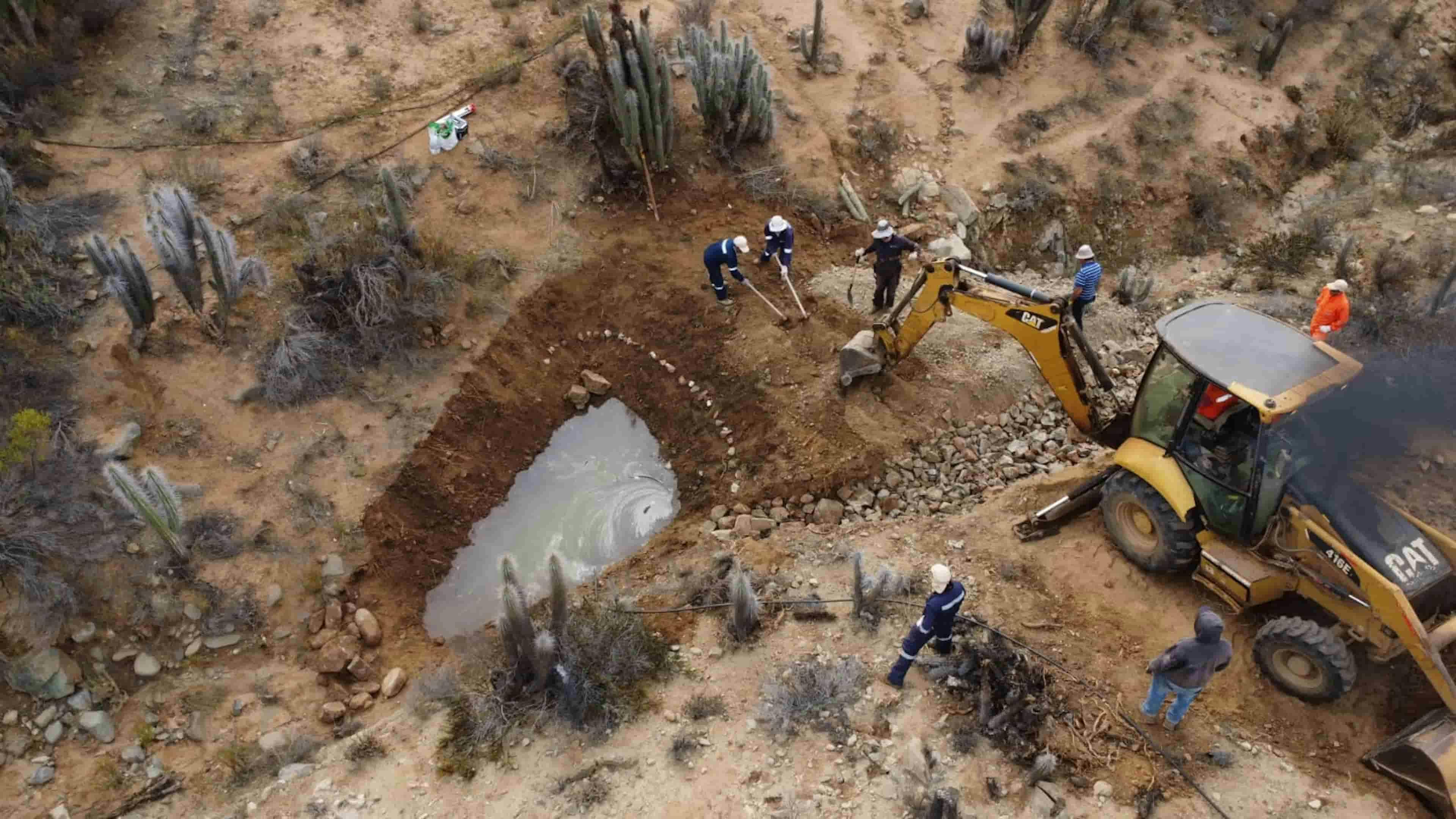 Overhead image of an excavator performing a water restoration project in a desert