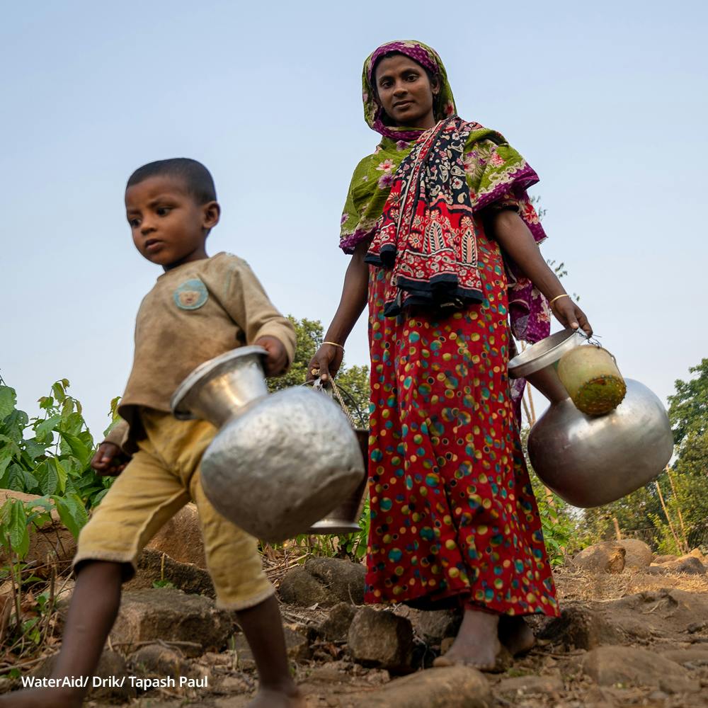 Khushnahar and her son carry two water cans, Bangladesh.